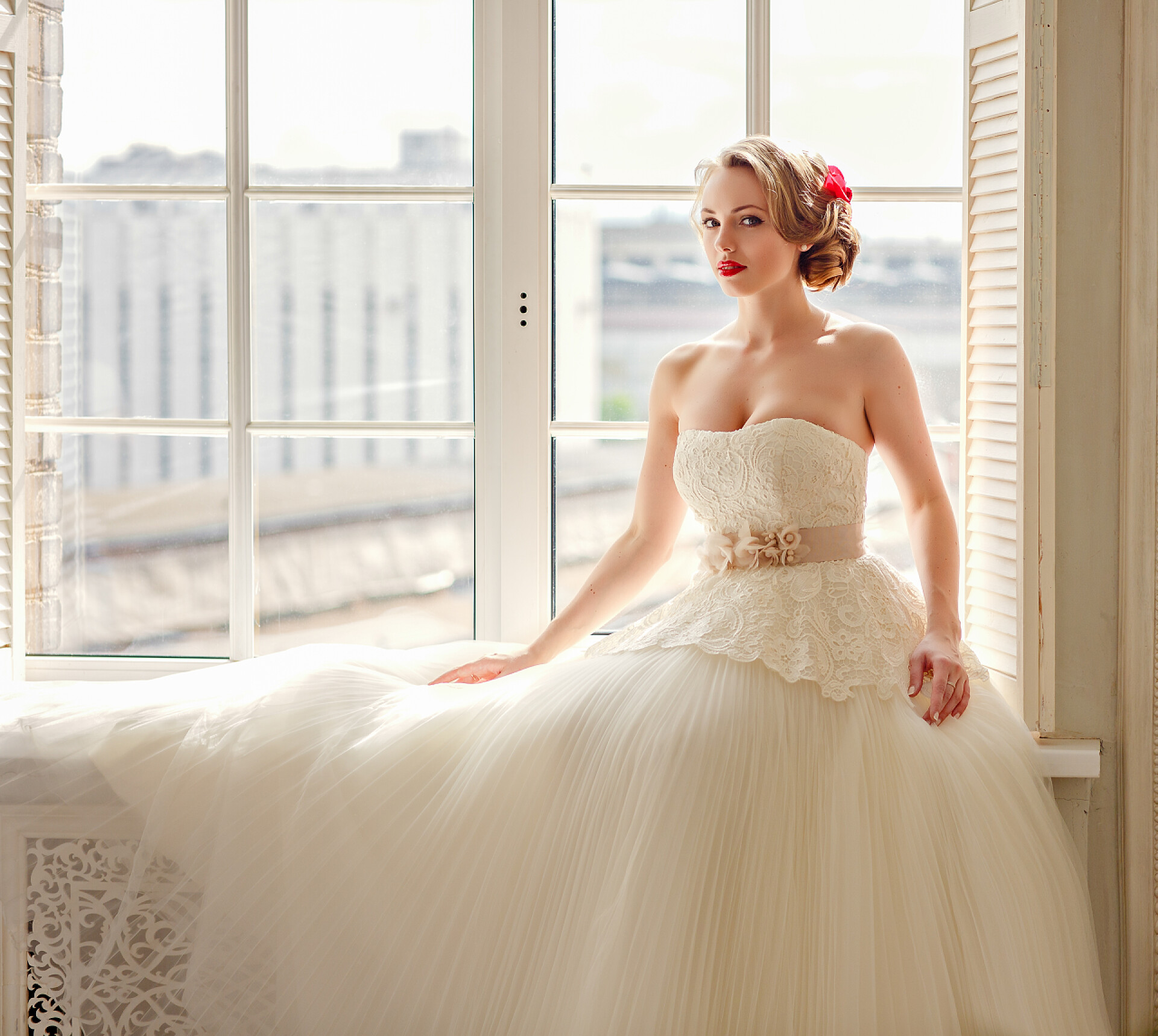 坐在窗台上的新娘Charming beautiful young blonde girl with red lipstick on her li