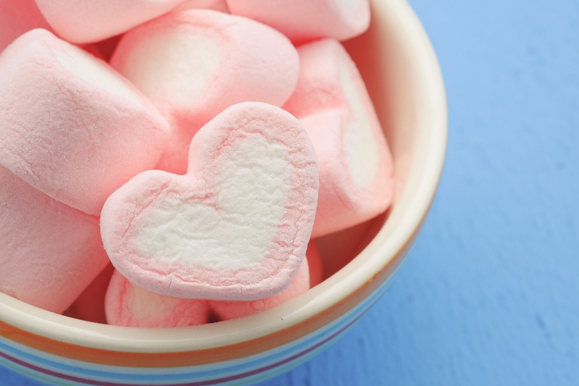 蓝色背景上的一碗棉花糖粉红色的心形状的棉花糖与滤波效果复古葡萄酒