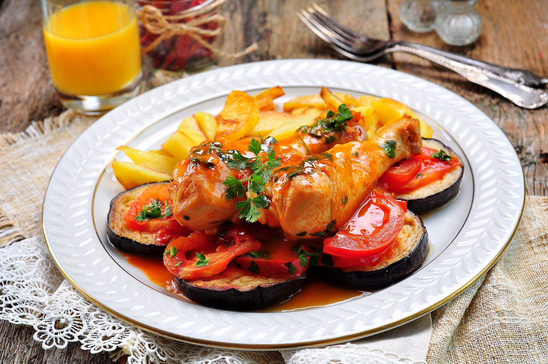 餐桌上的烧鸡茄子、 西红柿和薯条白葡萄酒烩的鸡.