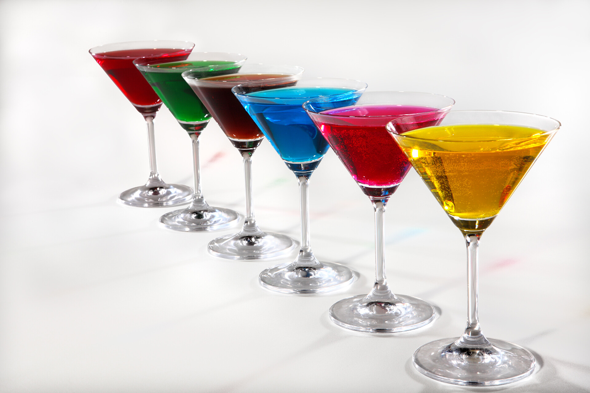 五颜六色的果汁在白色背景的小组玻璃与有色的饮料