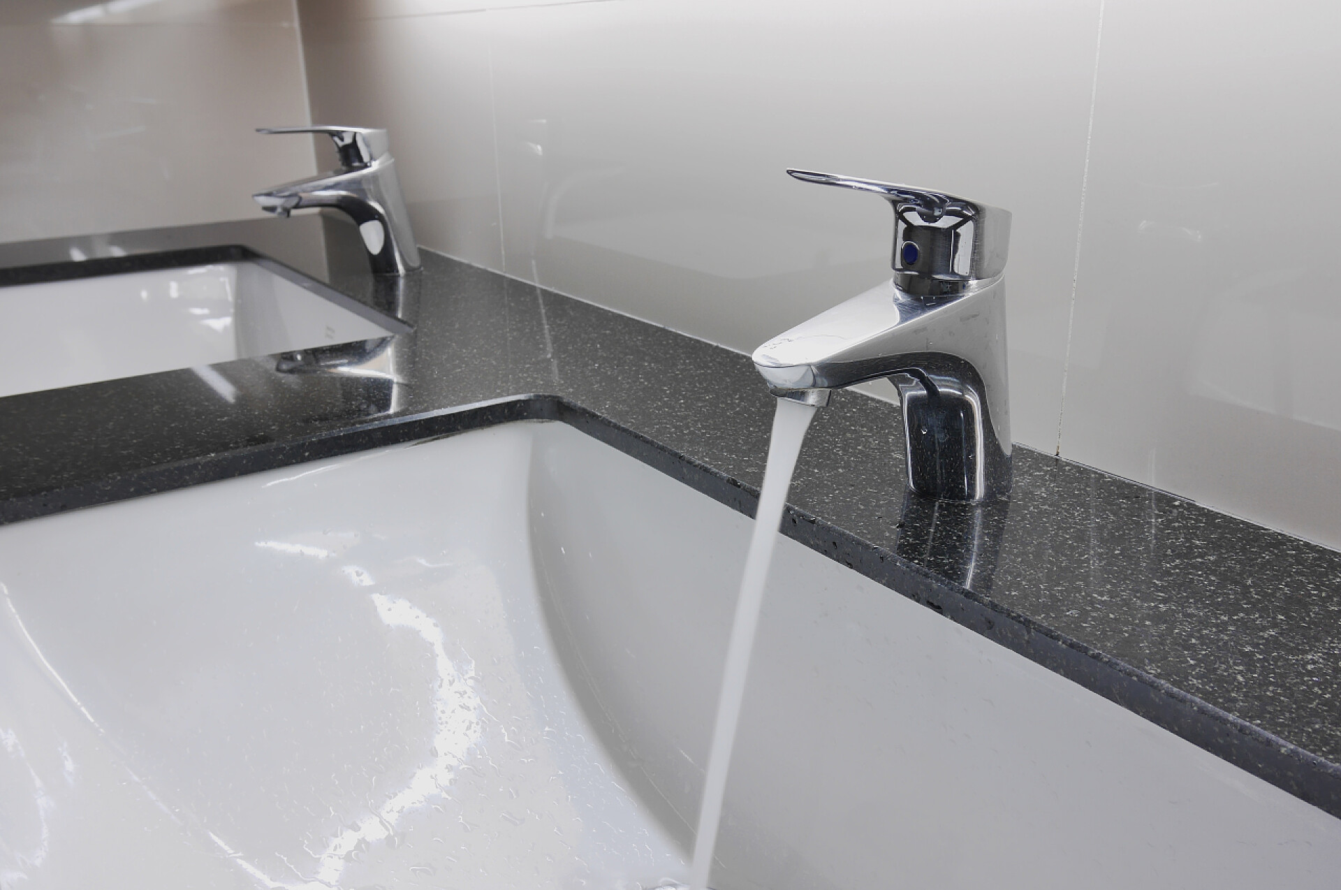 出水的水龙头白色的洗手盆和水龙头滴水与花岗岩柜台上