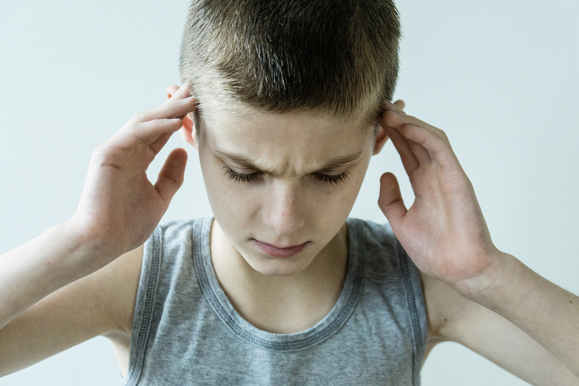 低头皱眉的小男孩肖像强调年轻男孩控股寺庙用手