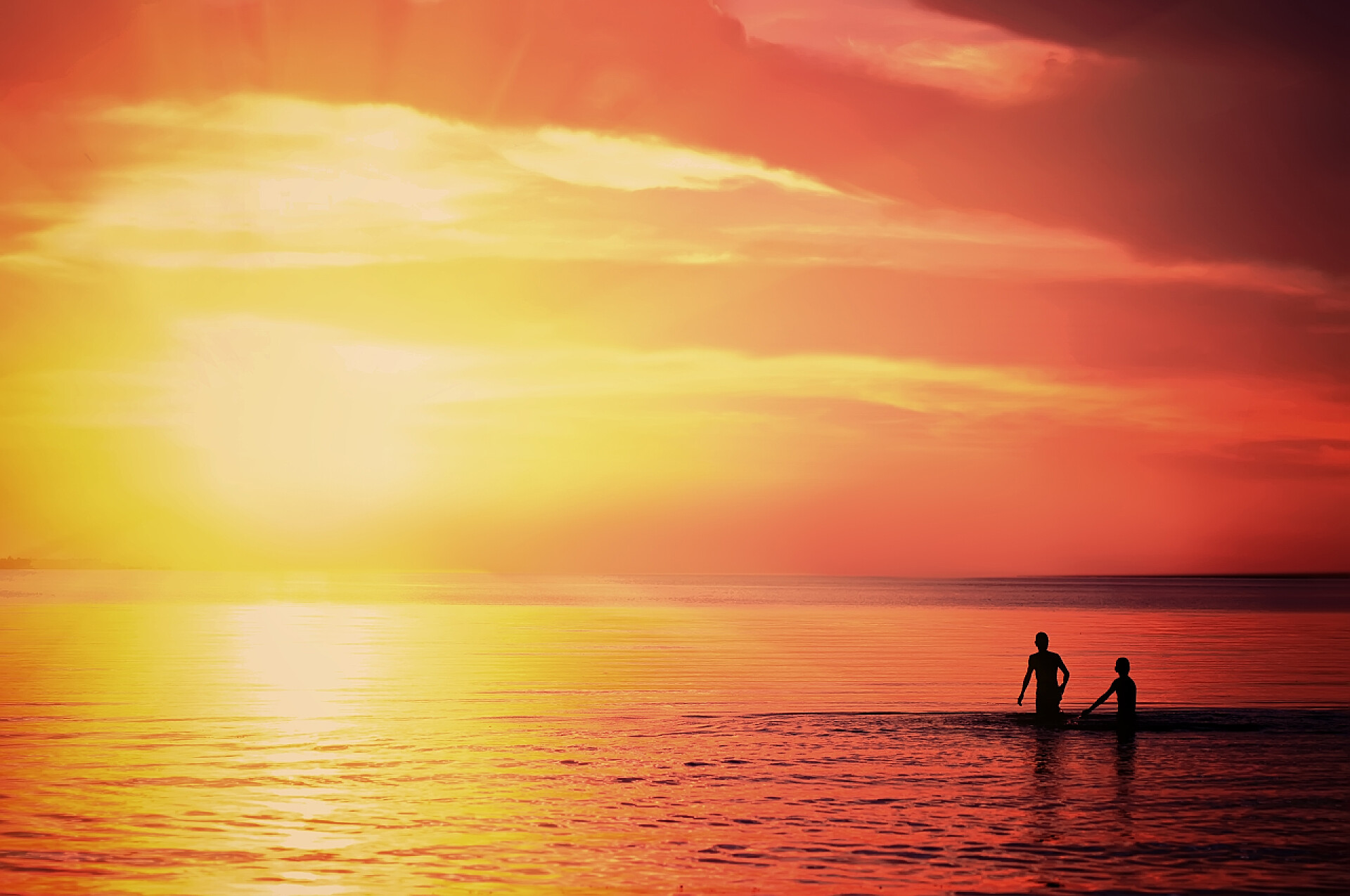 夕阳下在海边游泳的人两名男子在日落时分的海洋里游泳。自然夏天背景