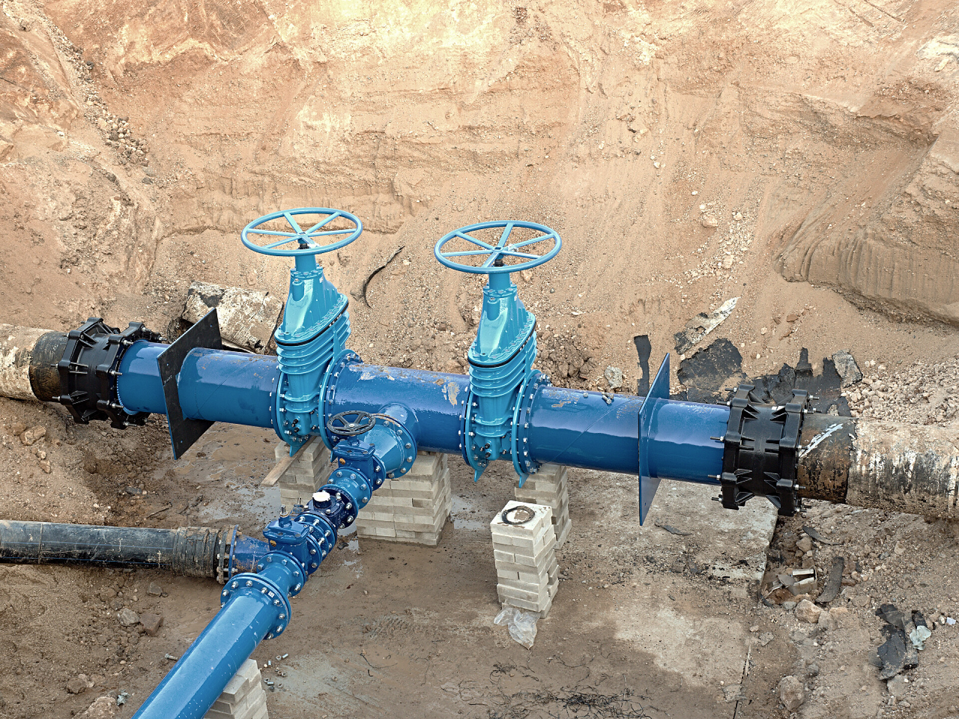 山间的饮用水管道500毫米饮用水管道与新的蓝色闸阀和新的黑色瓦加多关节成员连接. 