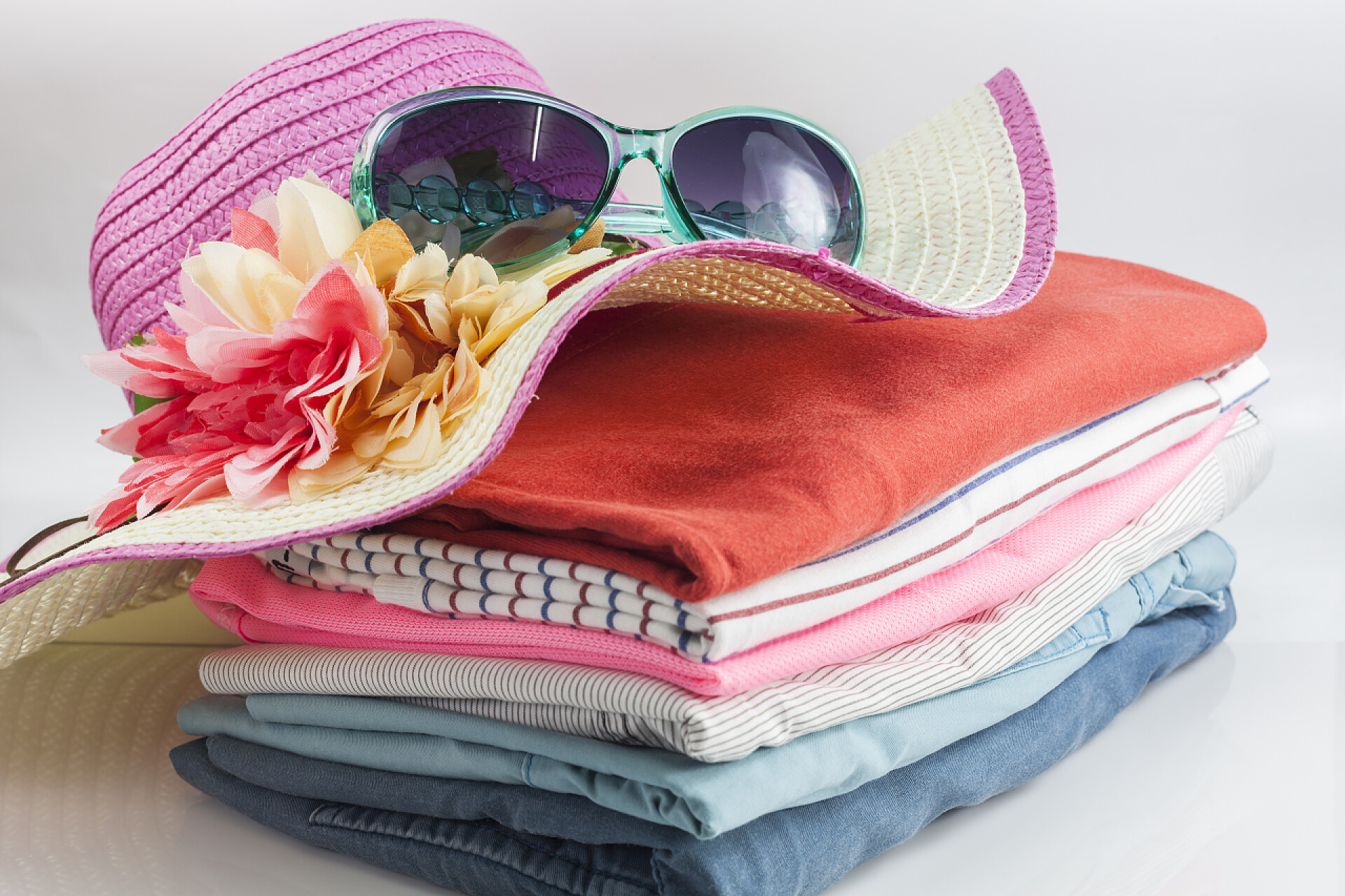 色彩鲜艳整齐的衣服一堆花花绿绿的衣服和美丽夏天帽子，甜美靓丽