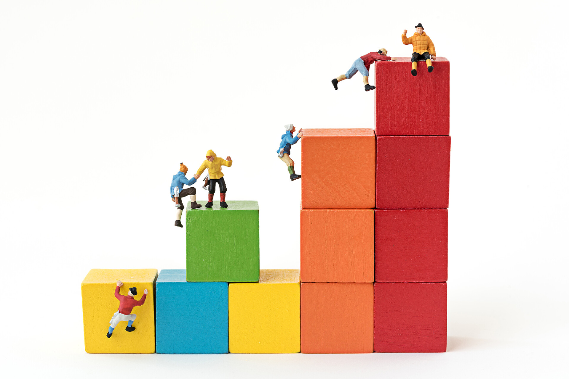 攀上的多维数据集构建基块的微型登山团队在多维数据集构建基块的堆栈上攀爬的微型登山团队