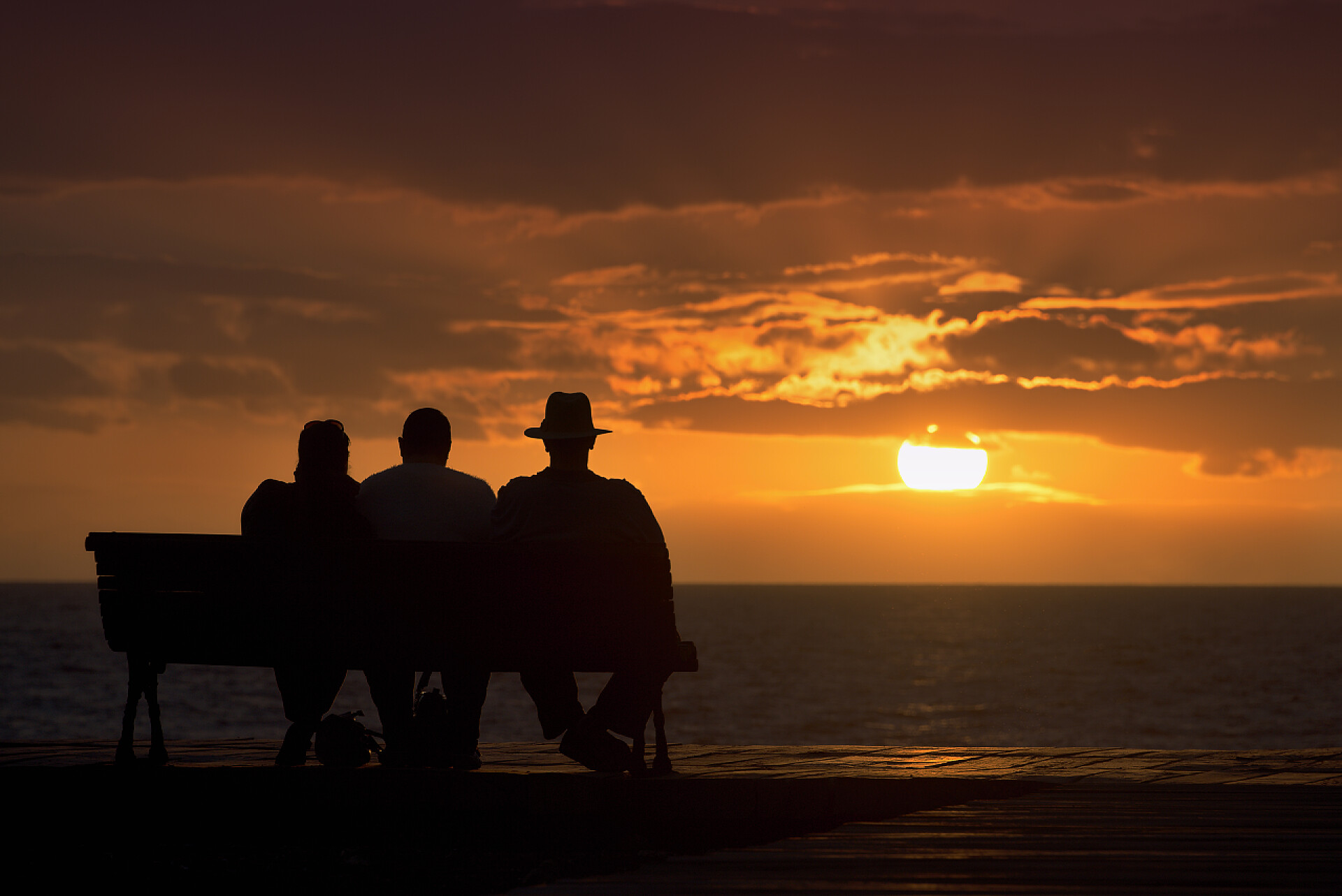 日落时分老人坐在长凳上的剪影组的老人坐在长凳上的剪影,