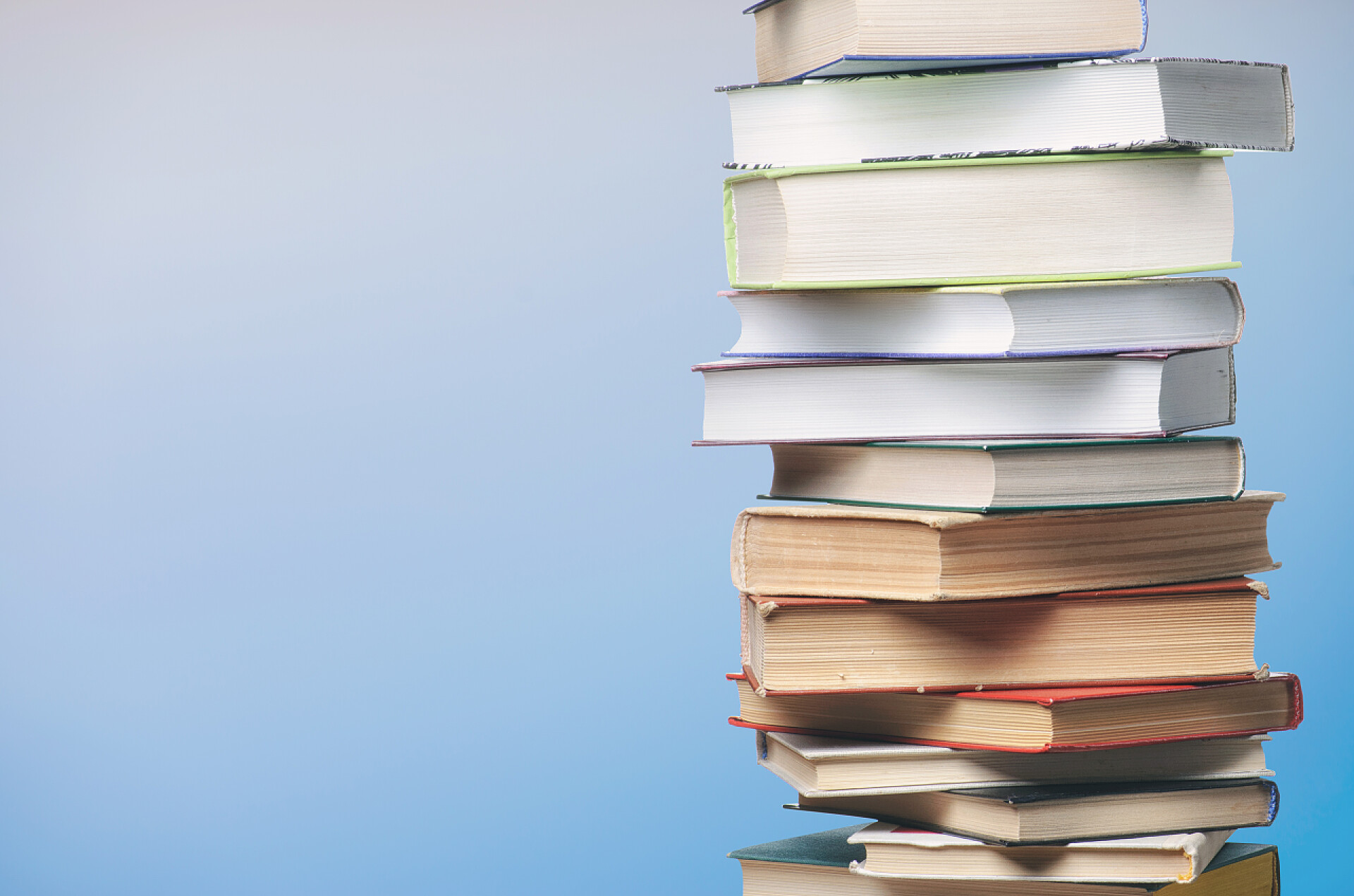 浅蓝色背景上堆砌的书籍蓝色背景上的书 