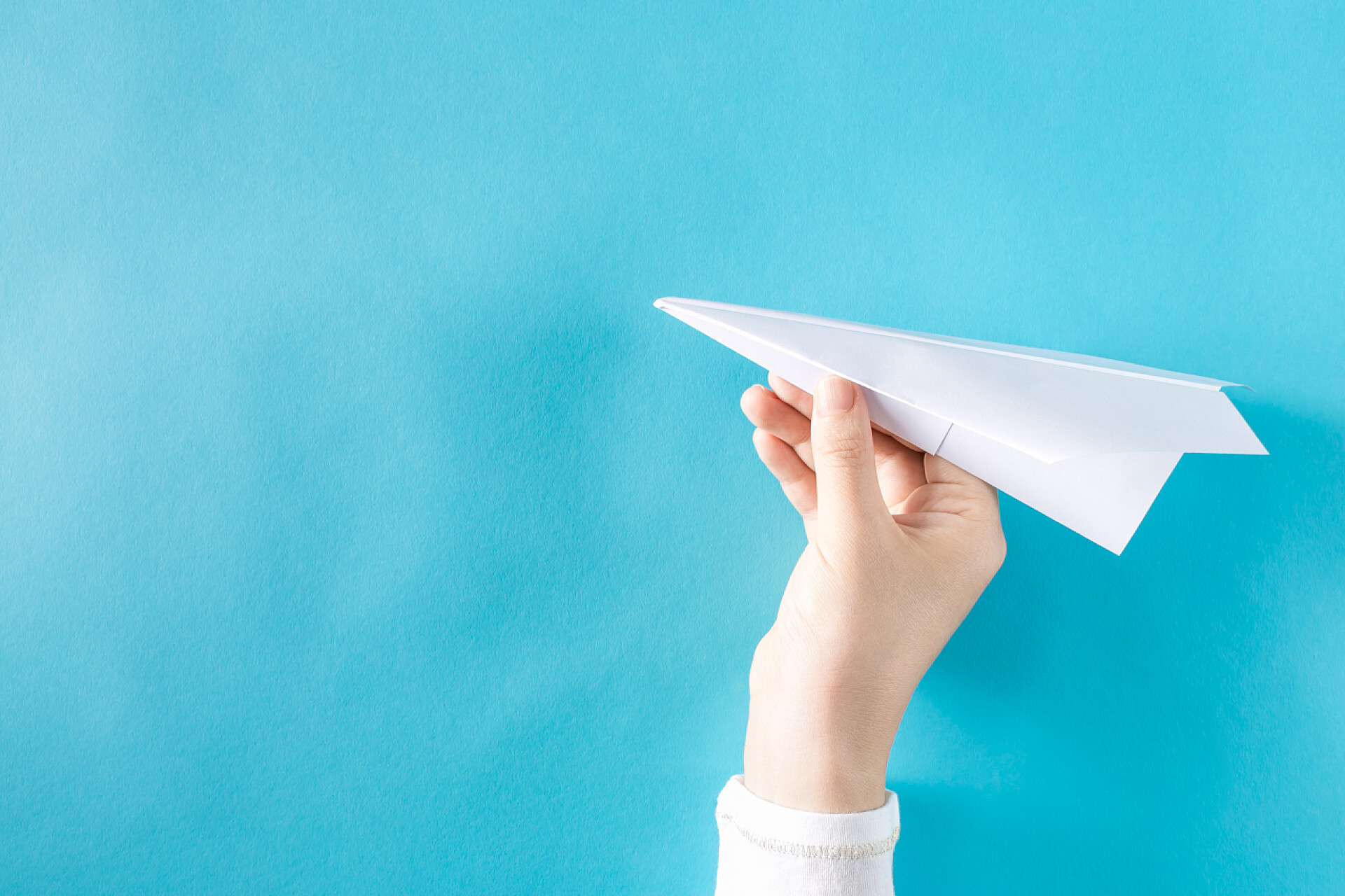 蓝色背景上手拿着纸飞机手拿着一架纸飞机