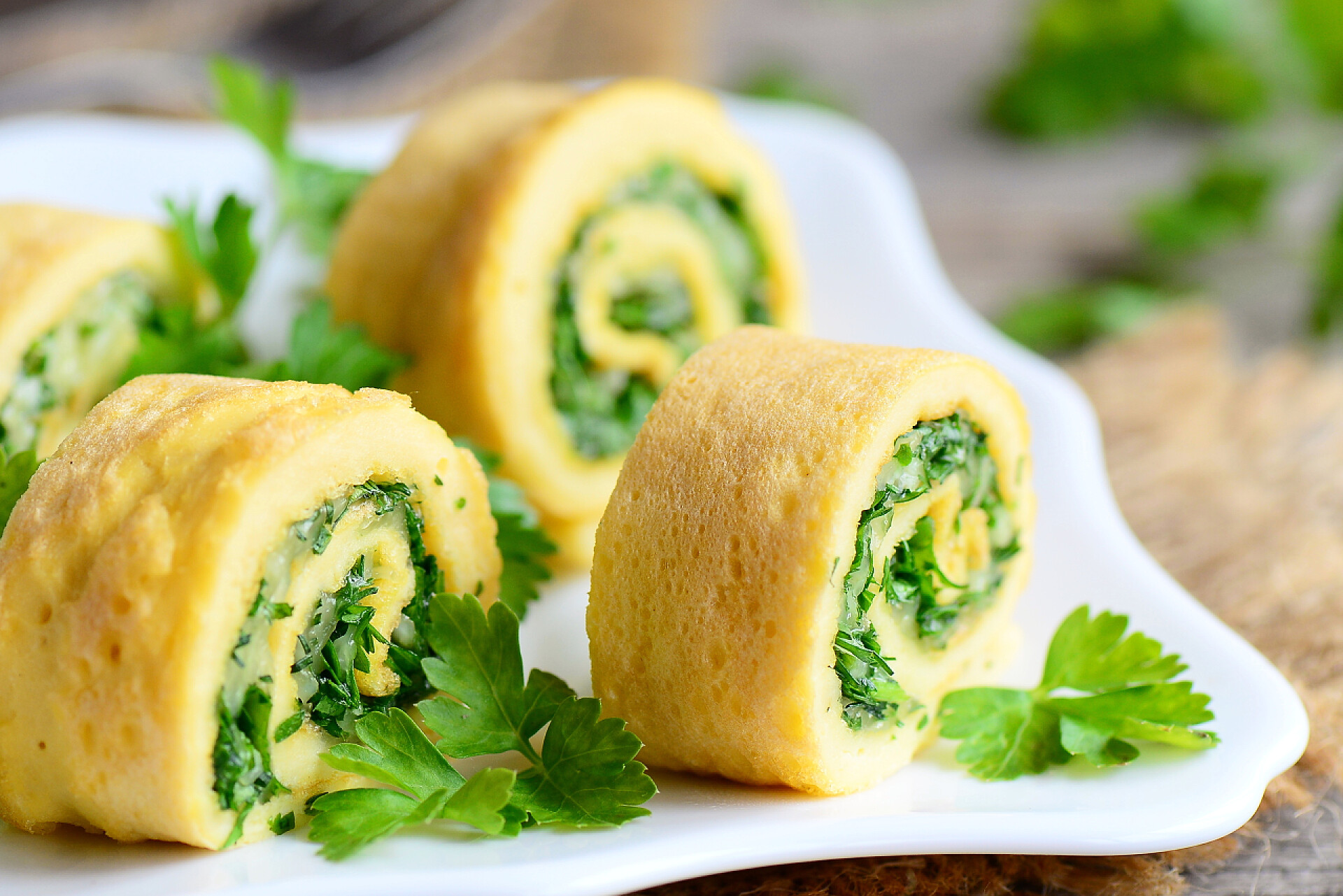 白色盘子里的蔬菜蛋卷奶酪和草药的毛绒的煎蛋。剪毛绒的煎蛋用磨碎的奶酪和切碎的香草。美味又健康的早餐的想法。乡村风格。特写