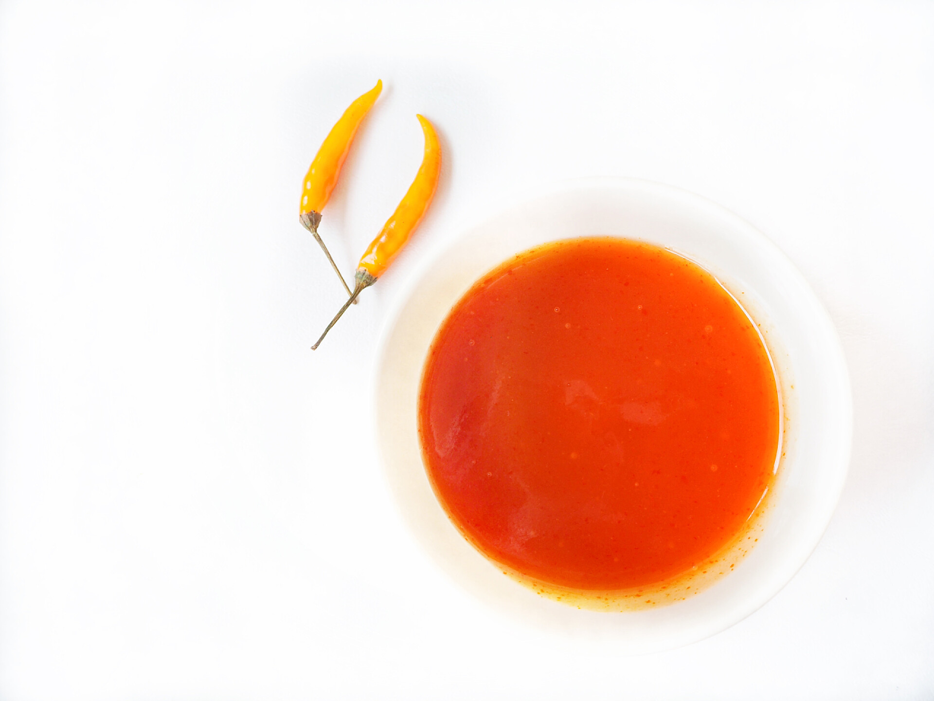 碗中盛着红色的辣椒油顶部视图的碗与拉差龙辣椒酱和生辣椒分离白色