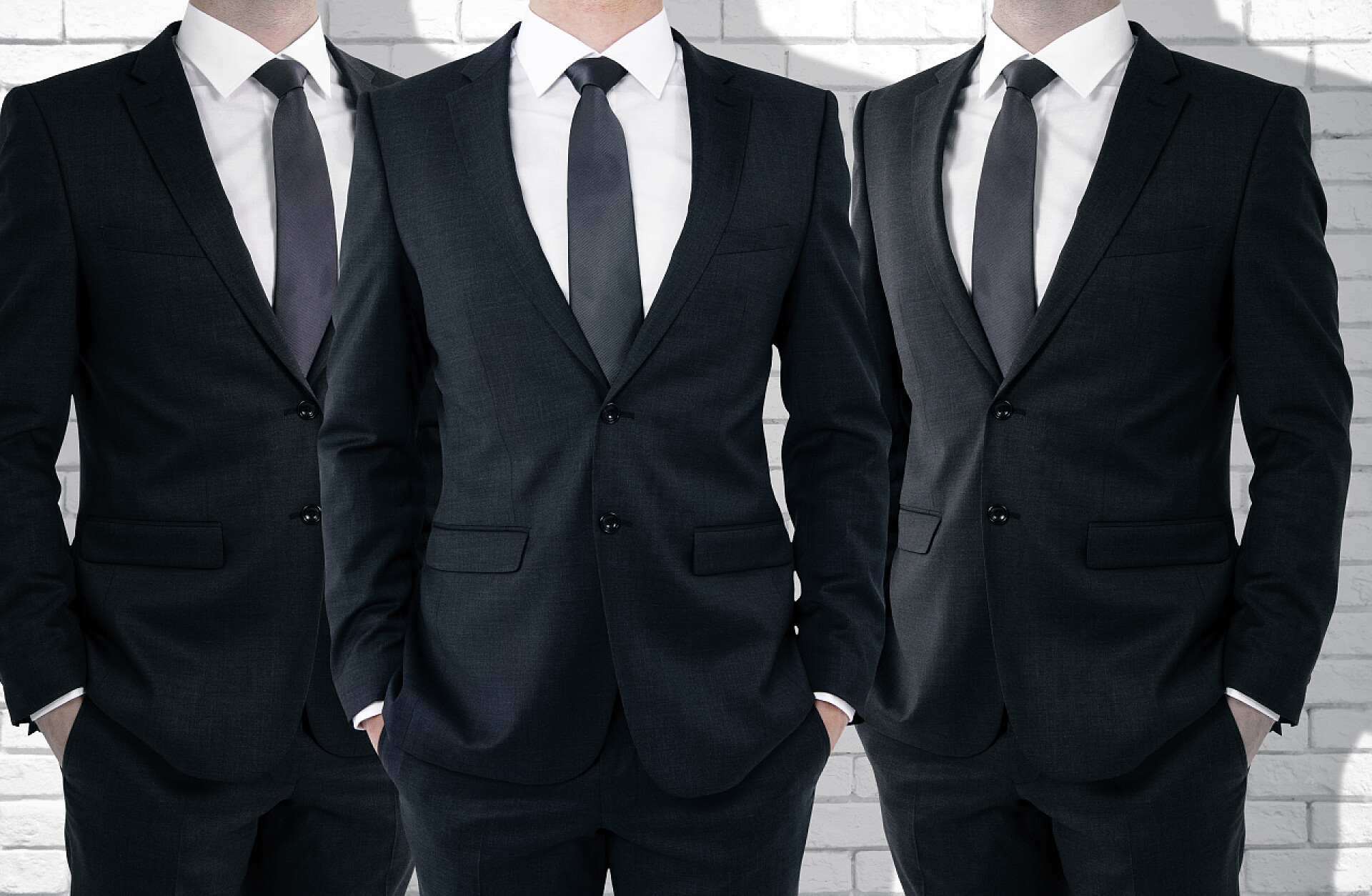 白墙前的男士西服展示图上白砖的背景墙上的三个变得面目全非商人.