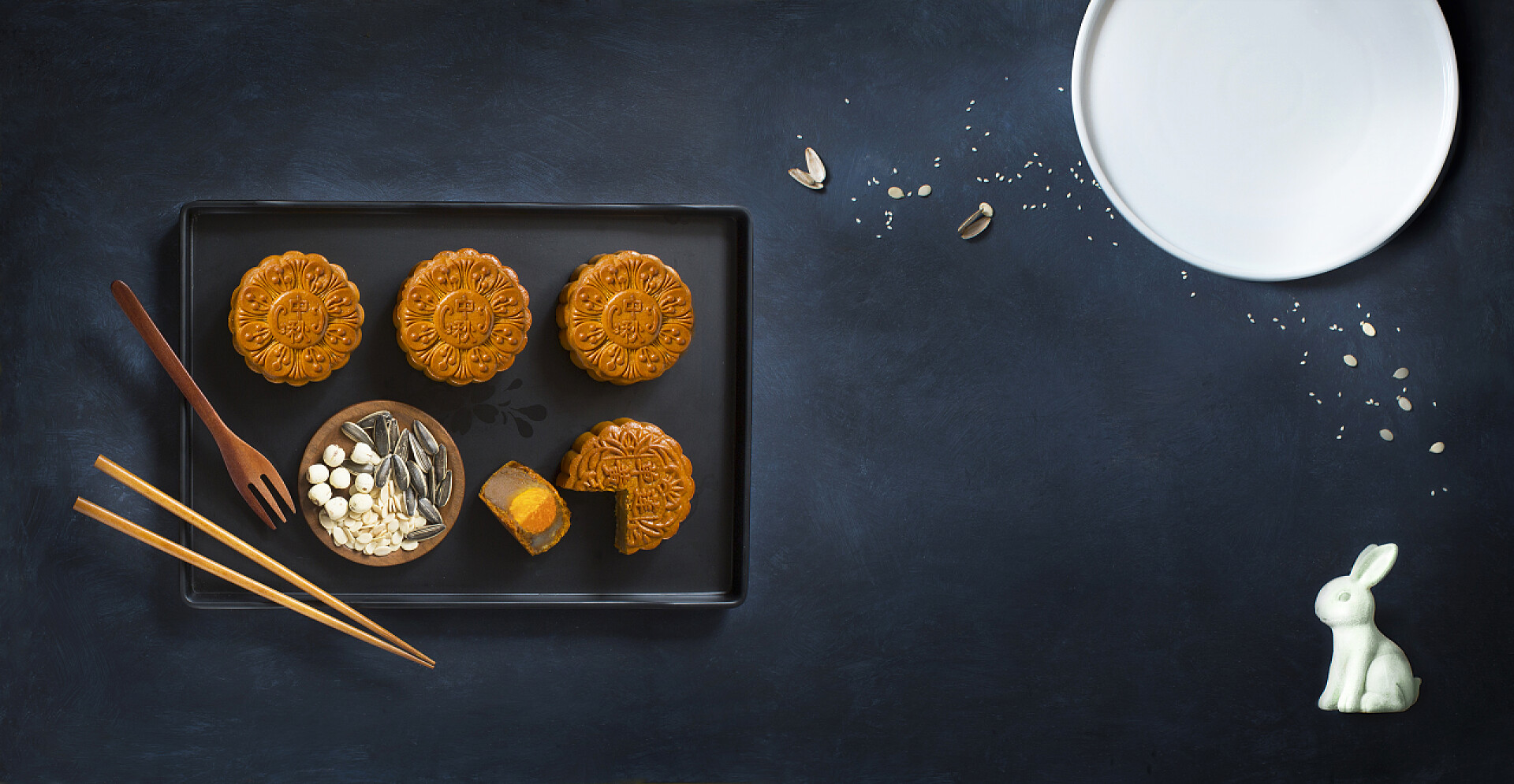黑色背景上放在托盘里的月饼和厨房用品仰视图概念平躺中秋节节日食品仍然生活在蓝色的乡村背景.