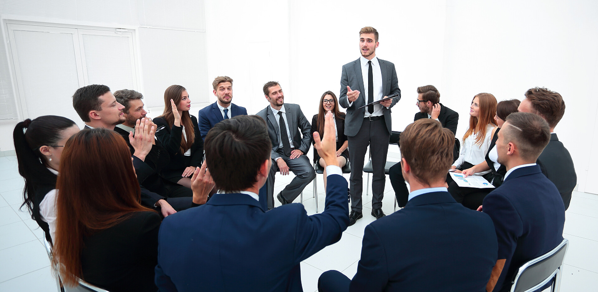 一个男人站在中间演讲熟练的教练向参加培训者提问.