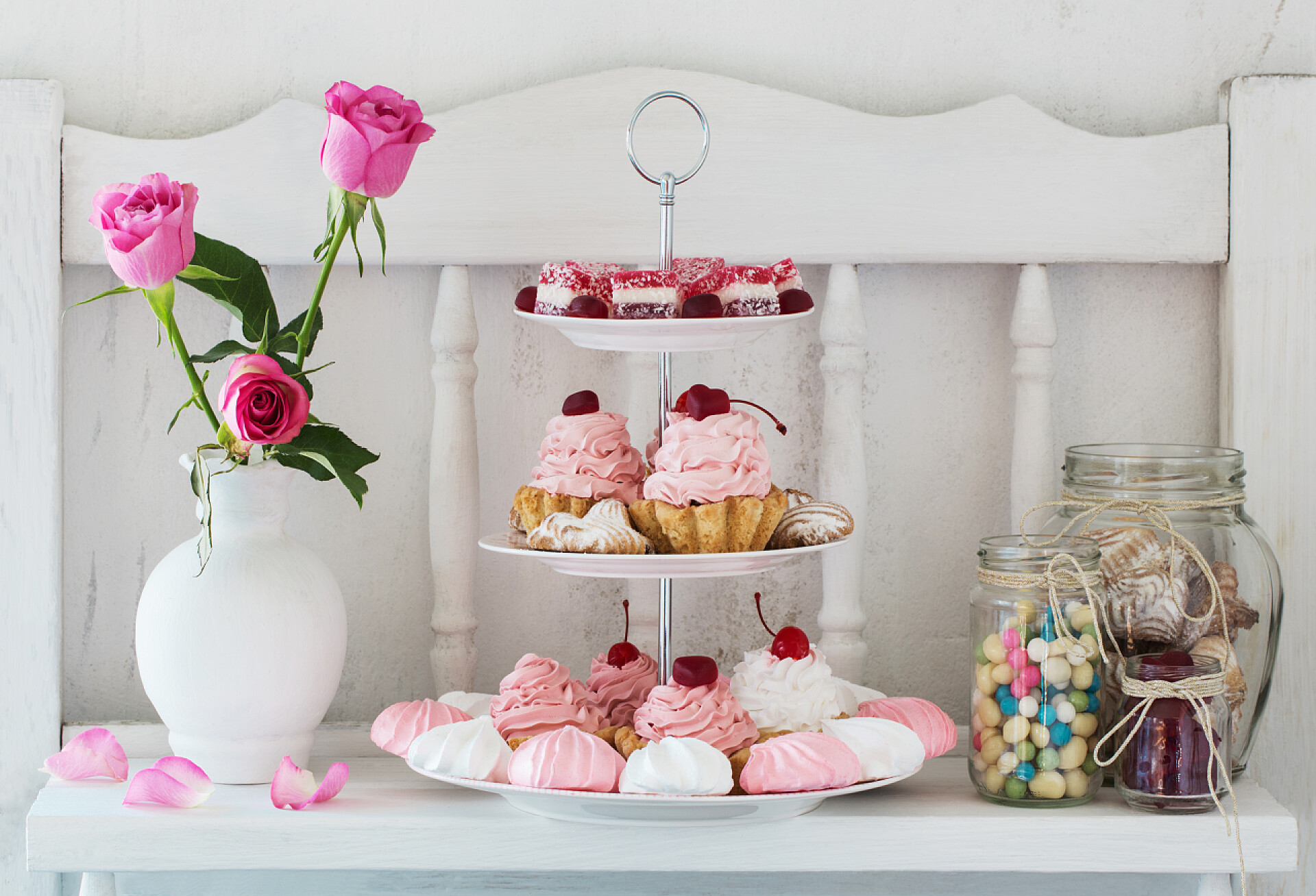 白色背景的凳子上摆放着甜品在白色背景板上的粉红色蛋糕