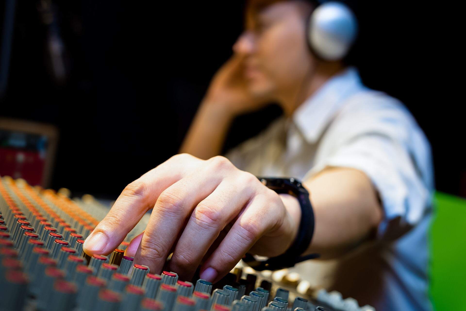 一个男人在调试调音台的音量音响工程师手在录音、广播演播室的音频混音控制台上工作