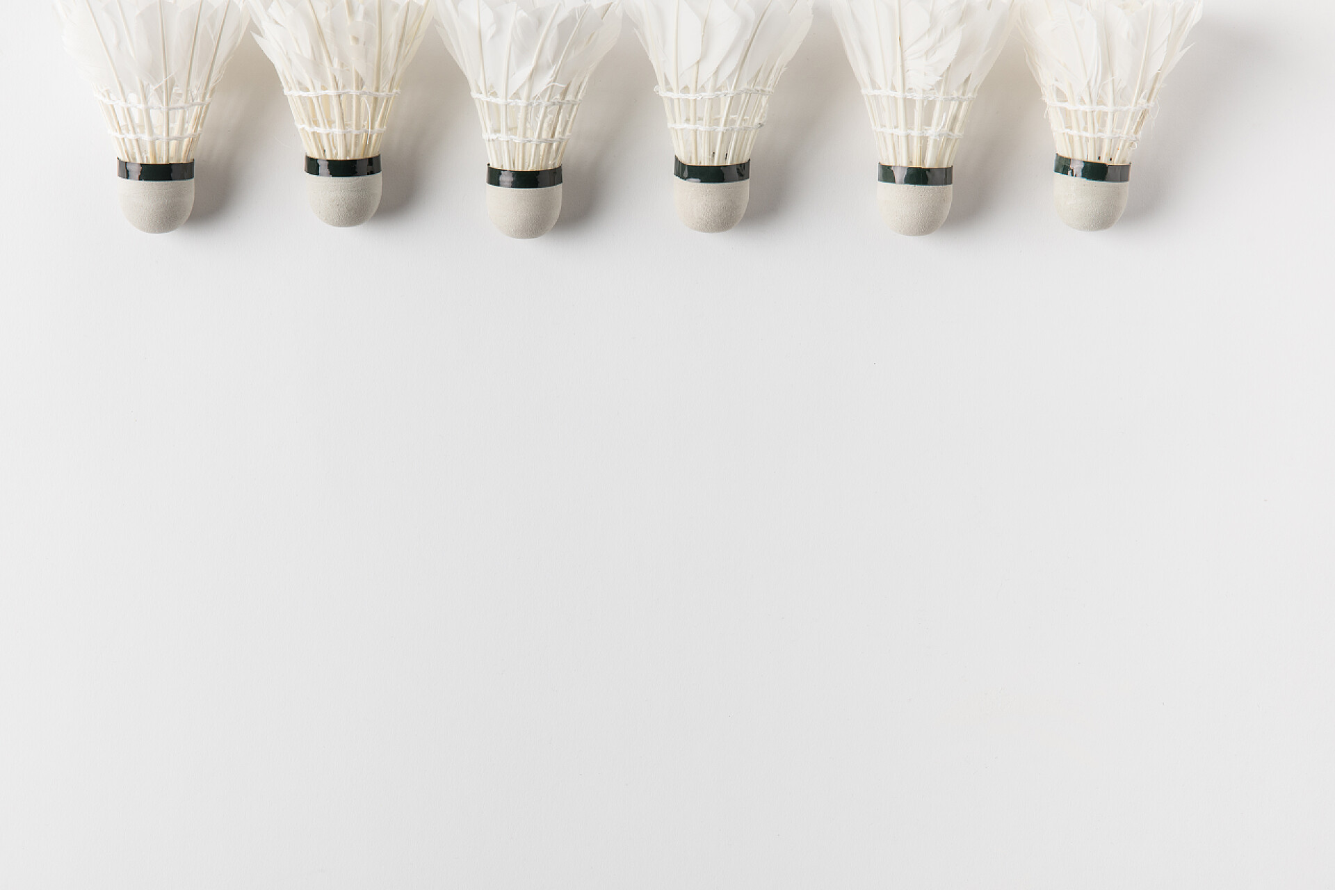 白色桌子上的一排羽毛球羽毛球羽毛球排在白色桌面上的复制空间的顶部视图