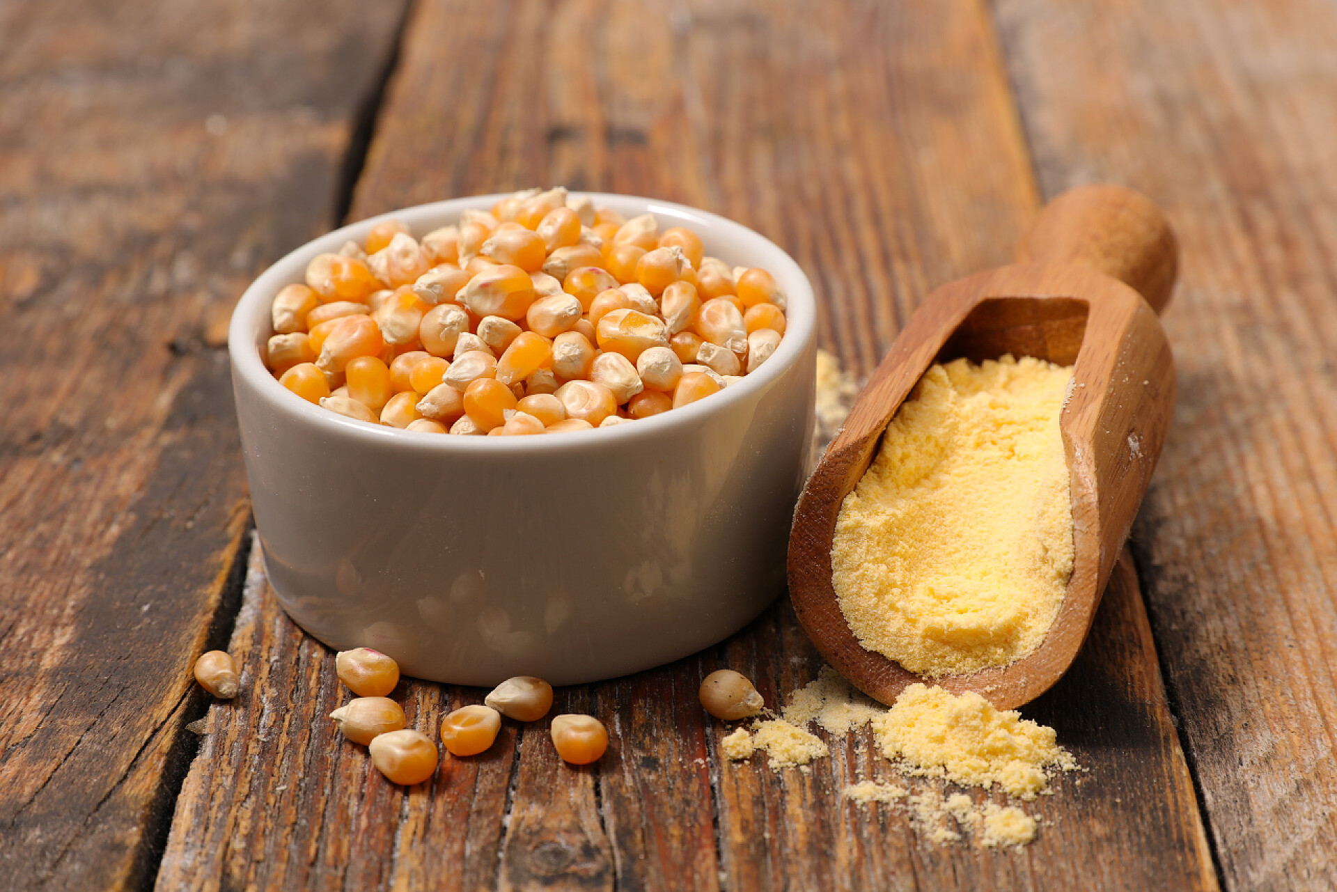 木质桌子上的玉米粒和玉米面粉木盆配玉米仁和汤匙配玉米粉