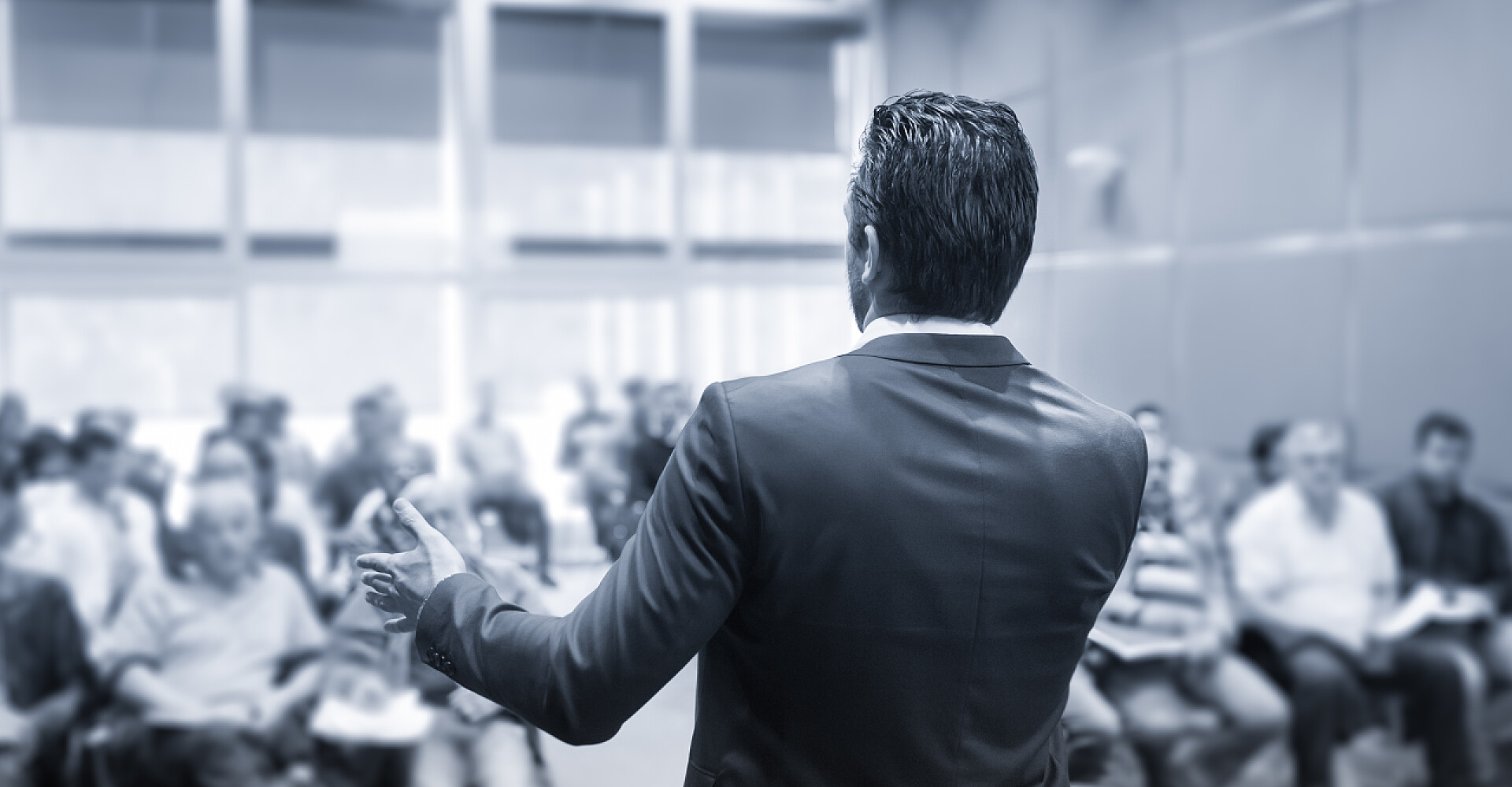 灰色背景下的一个男人在演讲讲者在商务会议上致辞.