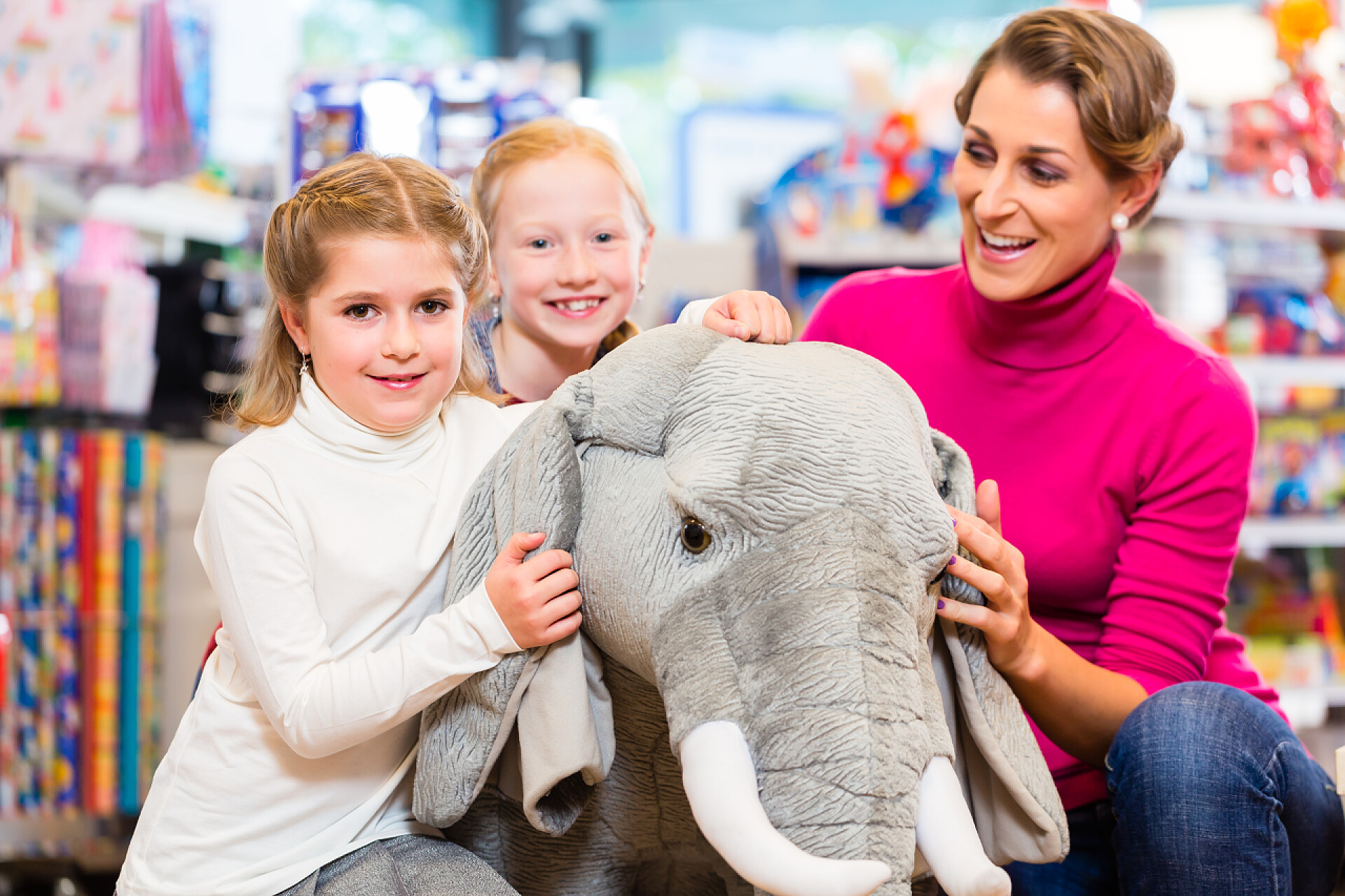 在玩具店里相中大象玩具的小女孩家庭在玩具商店拥抱与毛绒动物, 母亲与二个女儿
