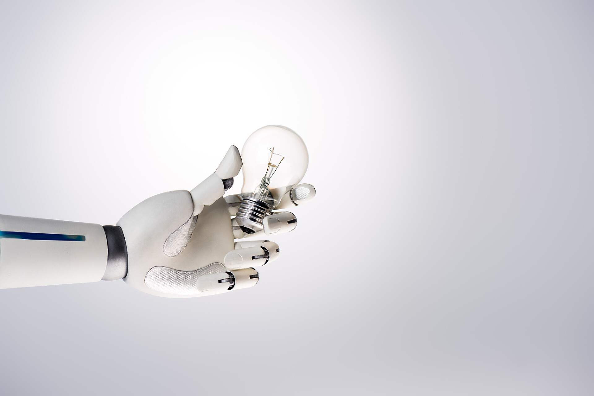 灰色背景墙一个机器人的手拿着灯泡想法