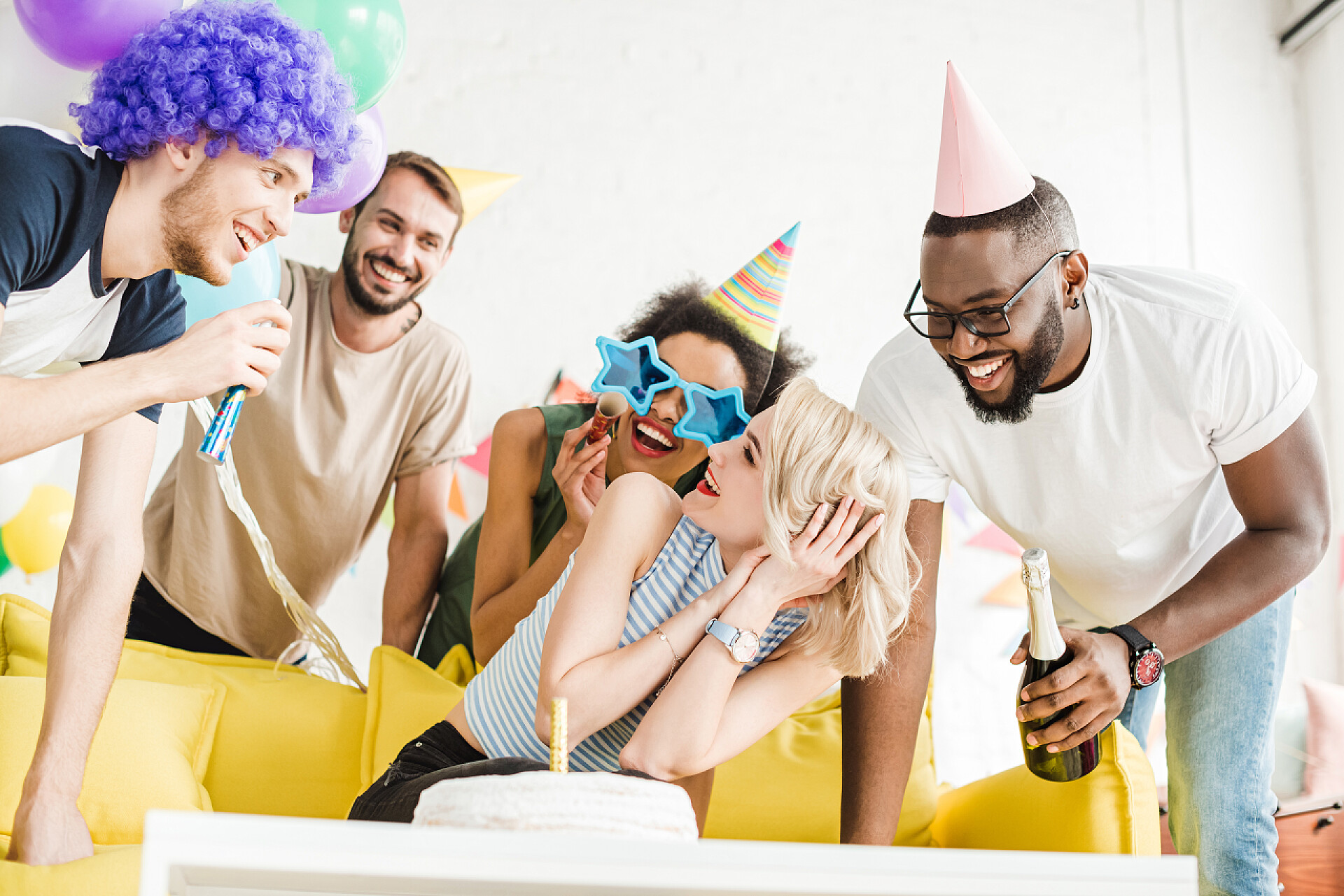 白色的背景下一群聚会的年轻人愉快的朋友问候金发女郎与生日蛋糕