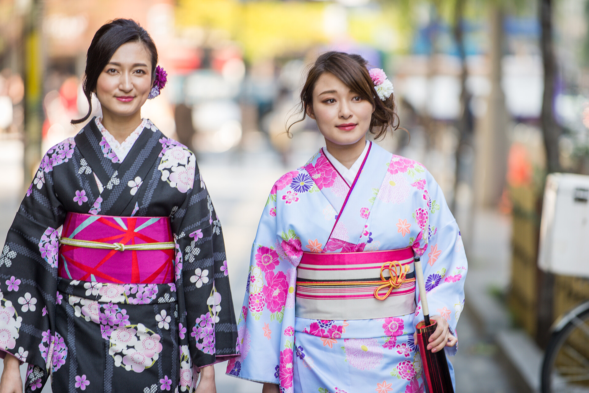 穿着日本和服的少女在街上散步两个穿着传统服饰的漂亮女孩在户外散步