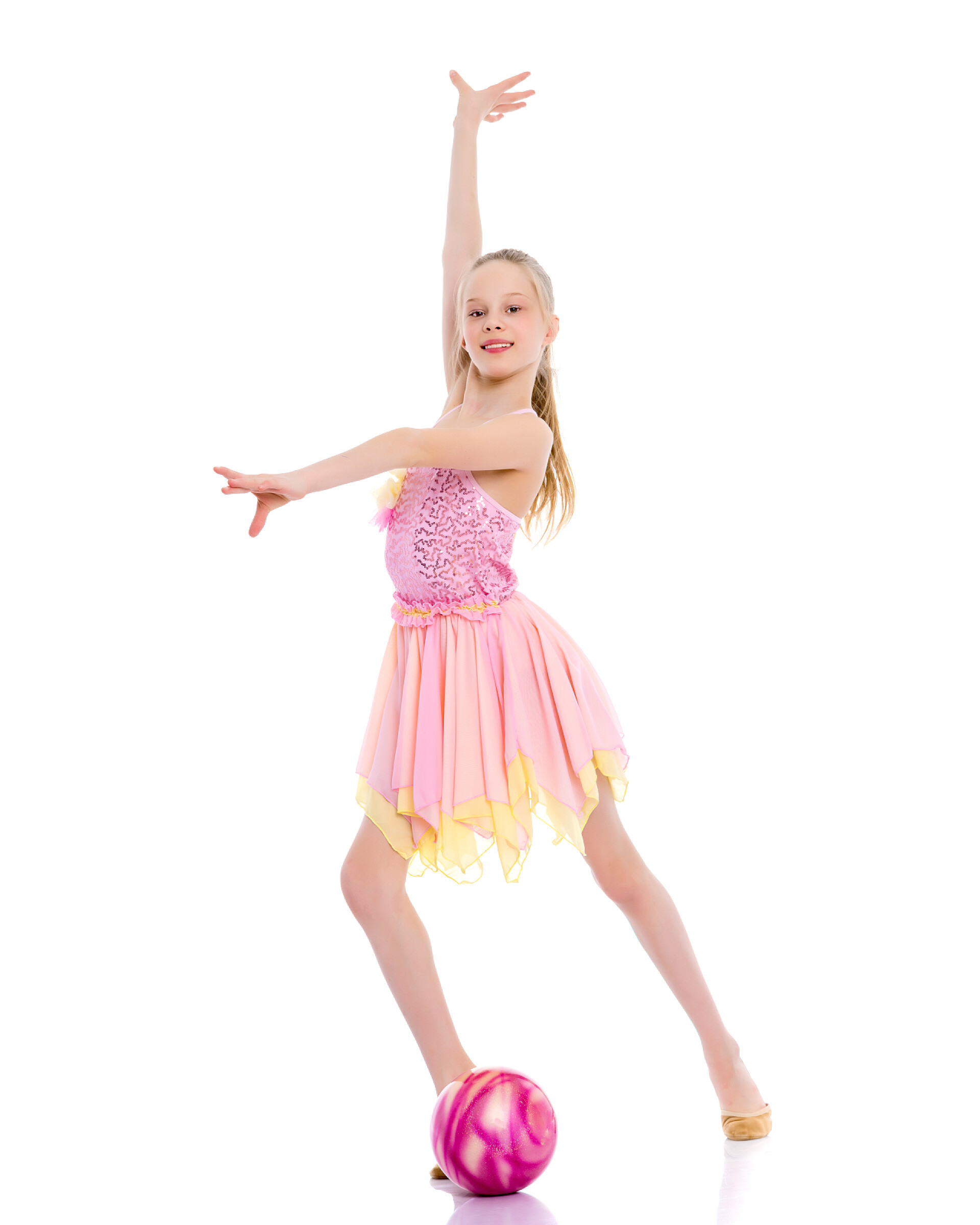 在白色背景前一个跳体操的小女孩女子体操运动员用球进行练习.