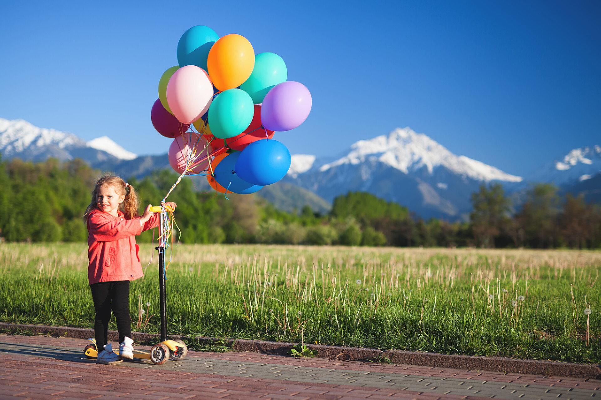 儿童节气球儿童节人像儿童节图片61儿童节蓝天白云下的小女孩拿着气球孩子们学会在阳光灿烂的夏天一天骑滑板车在公园里。学龄前儿童男孩和女孩在安全头盔骑滚子。孩子们在户外玩滑板车。积极的休闲活动和户外运动的孩子.