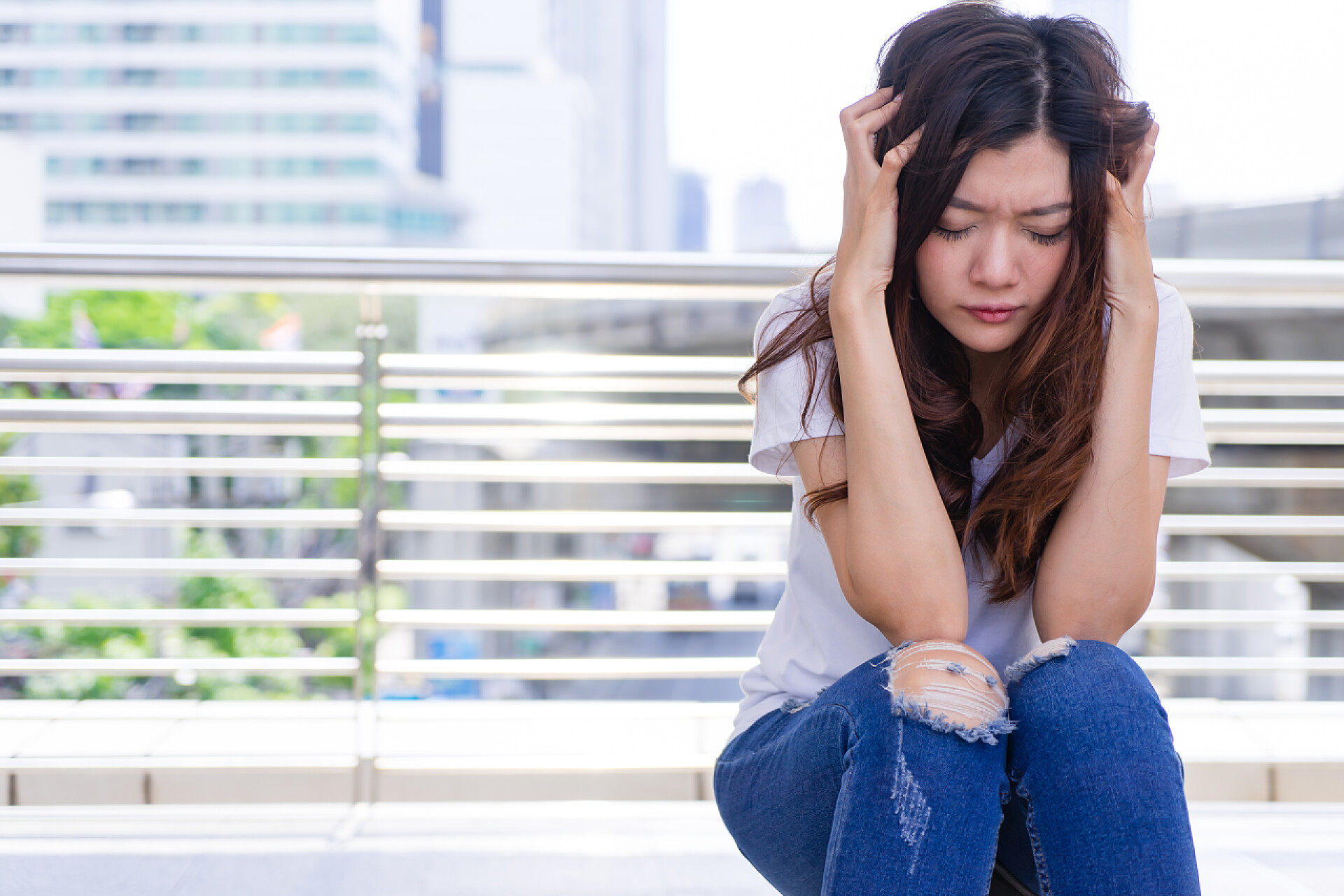 坐在地上悲伤的女人强调悲伤的女人头痛。不安的女人握着她的头在她的手中.
