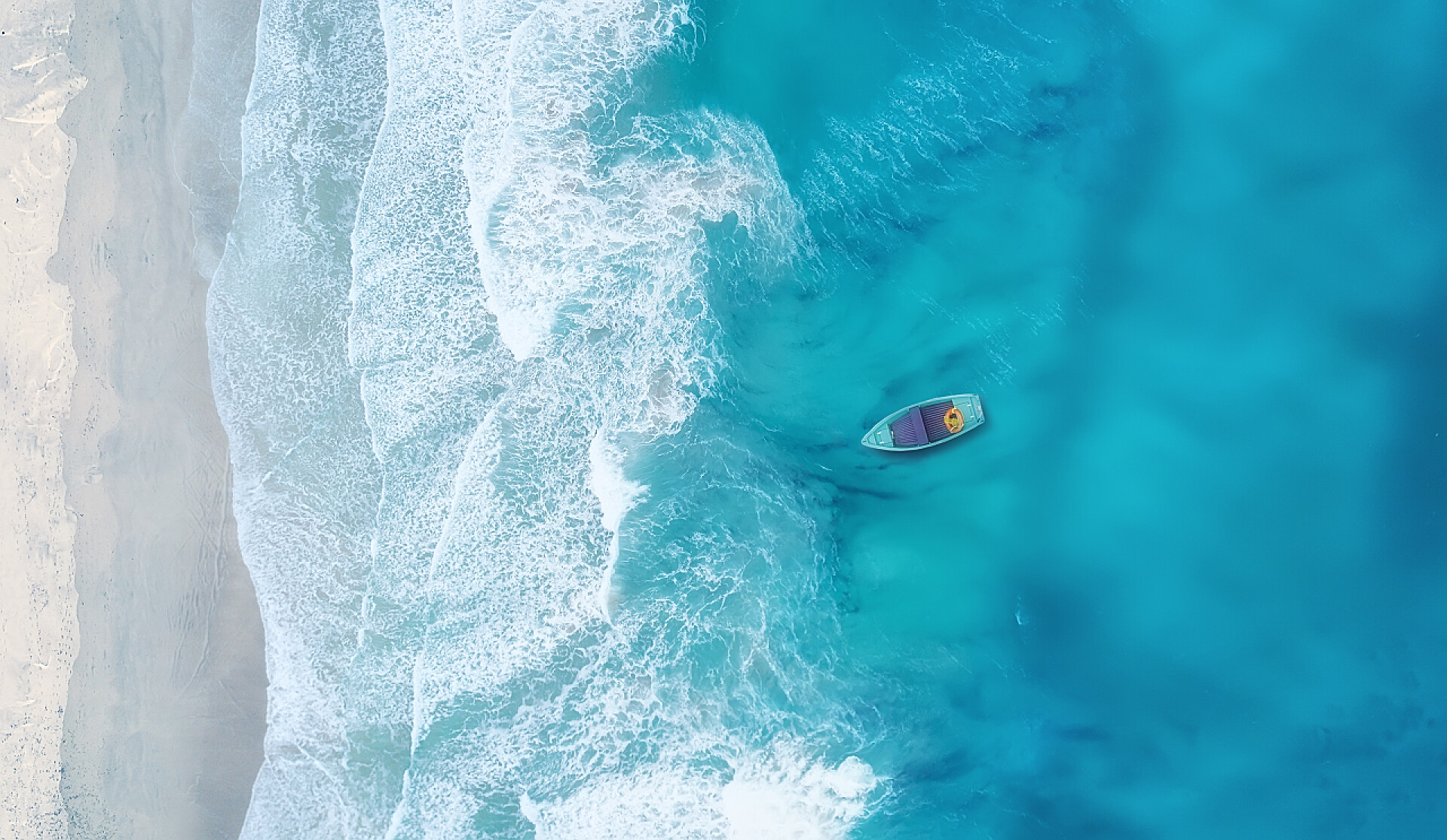 夏天风景从上俯瞰的蓝色大海和沙滩波浪和小船在海滩作为背景。美丽的自然背景在夏天时间从空气