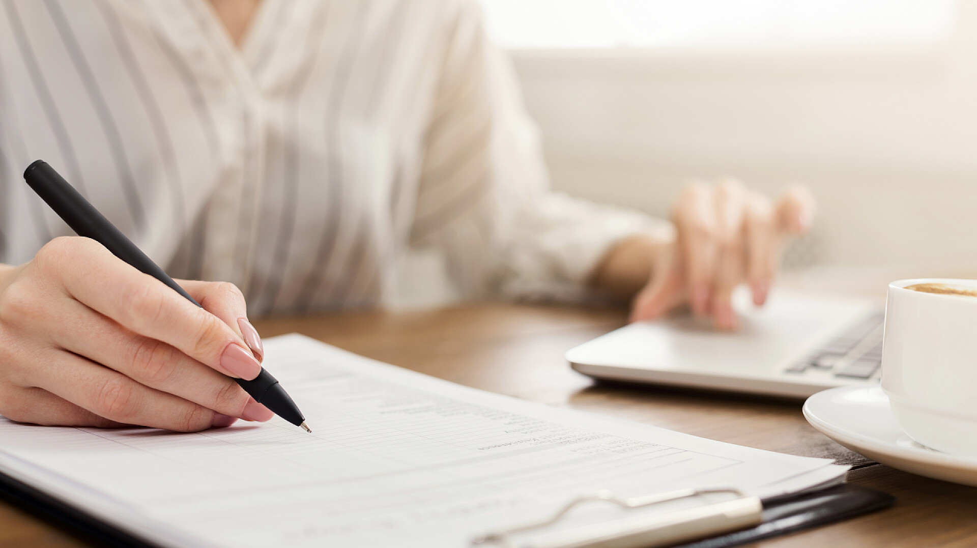 木质桌子上在写作的女人年轻女企业家在手提电脑和写笔记