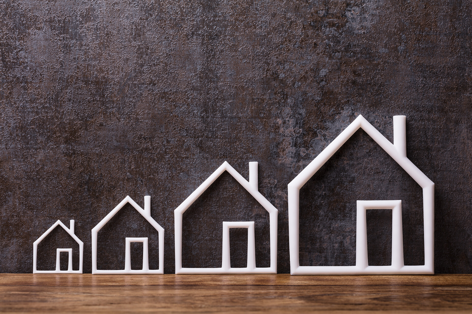 黑色背景墙前的从小到大的房子在乡村背景下增加白色外型住房