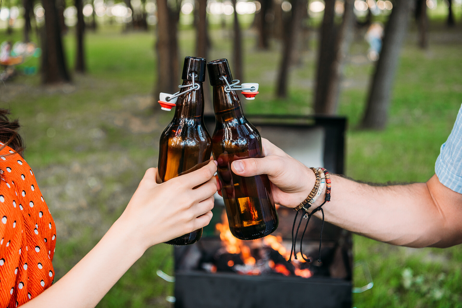 在公园里喝酒的两个人公园烧烤期间夫妇无比啤酒瓶的裁剪拍摄