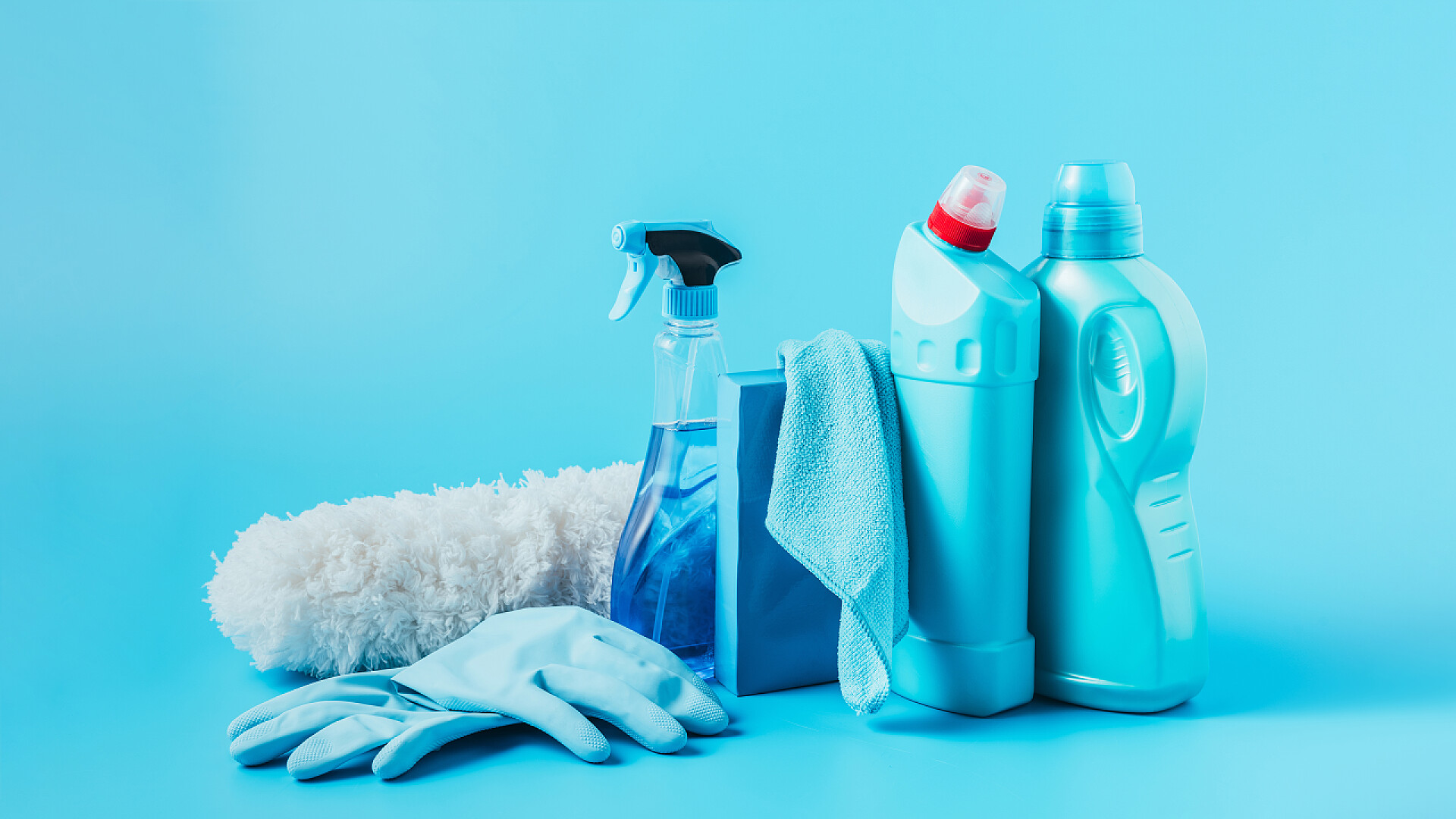 蓝色背景下的清洁工具在蓝色背景下关闭除尘器、橡胶手套、清洗液、洗衣粉、抹布和洗衣液的全景图 