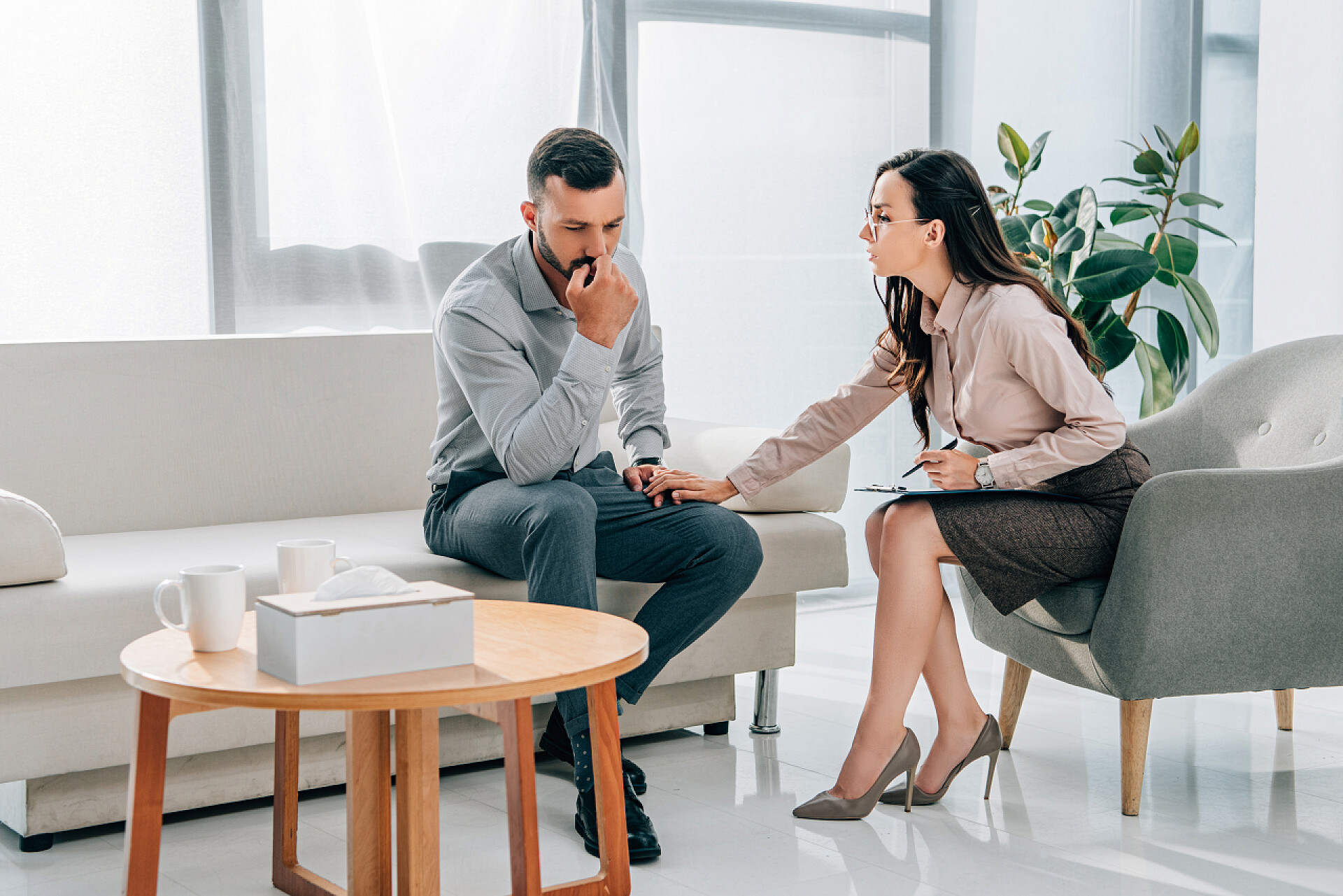 一个女人在安慰伤心的男人女性心理学家和患者在办公室咨询