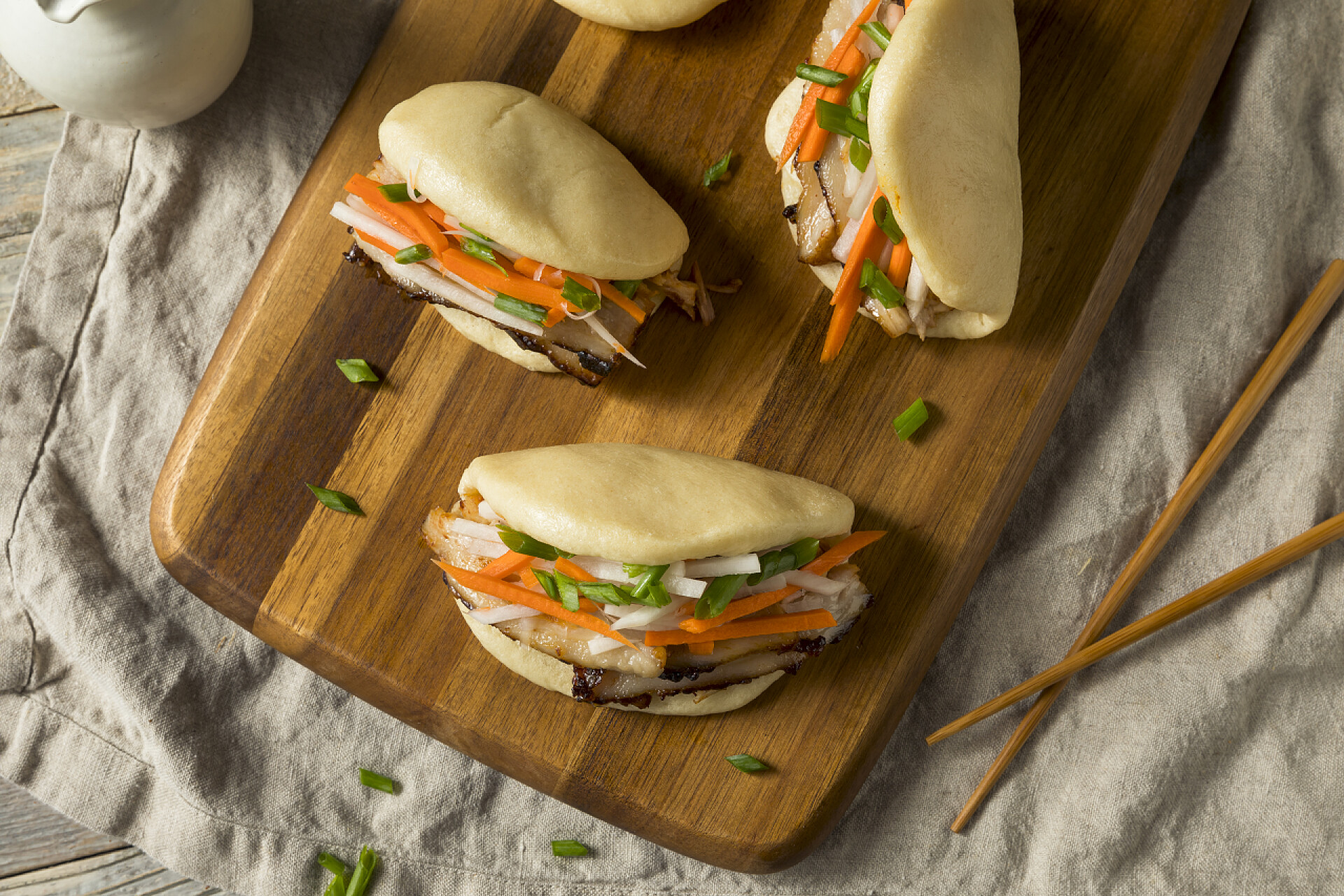 木制的菜板上的三个夹馅馒头自制清蒸猪肉肚包配蔬菜