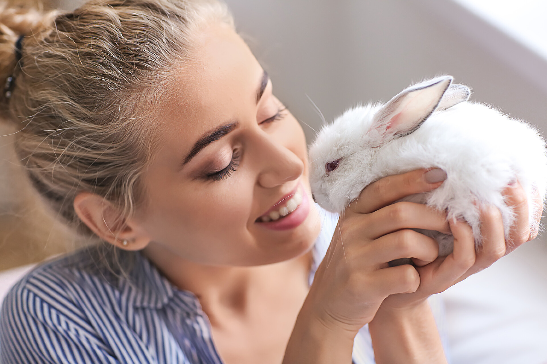 一个美丽的女人抱着可爱的小兔子可爱的兔子在家里的美丽的年轻妇女