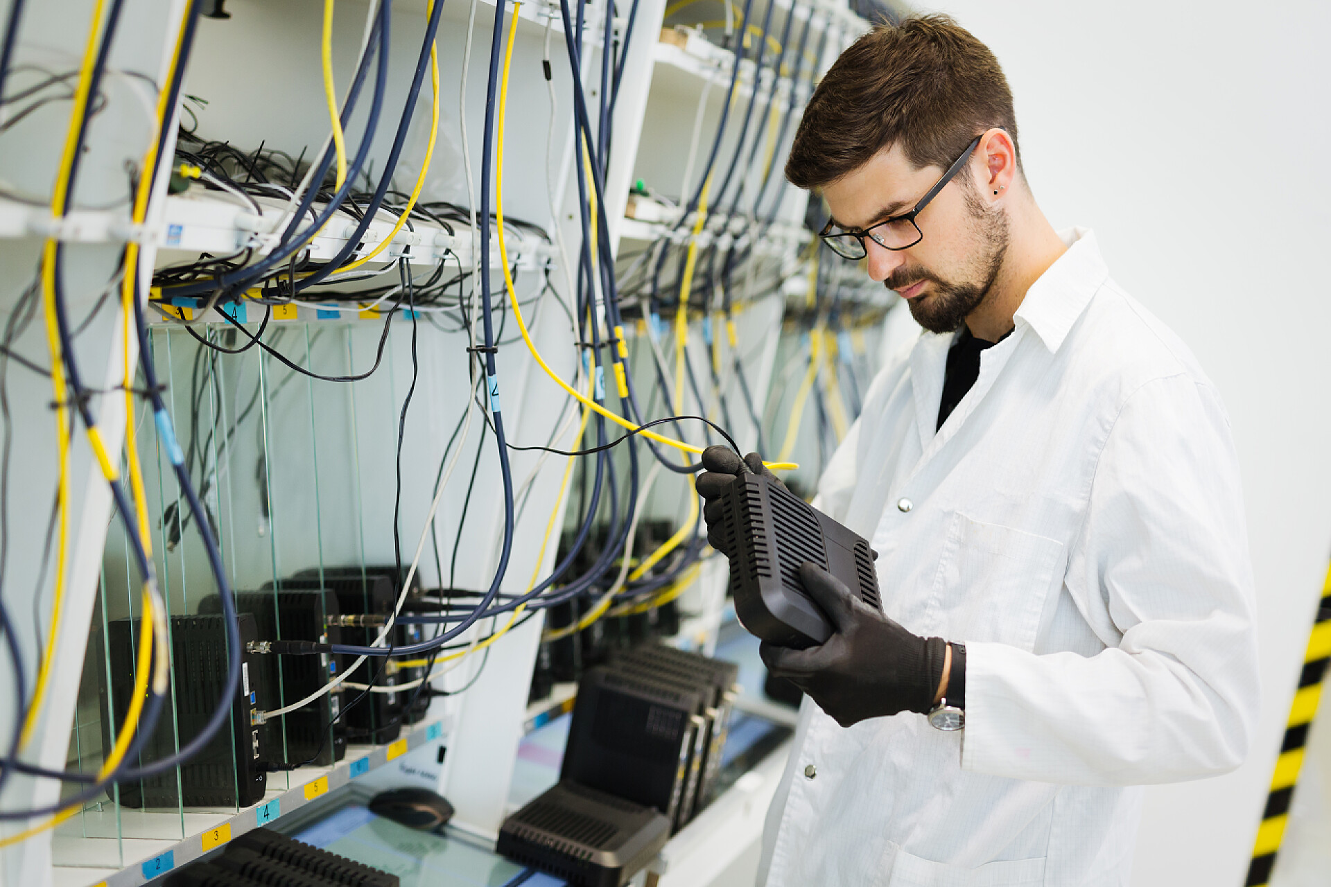 一个穿着白大褂的男人在做网络调试网络技术员工程师在工厂测试调制解调器的图片