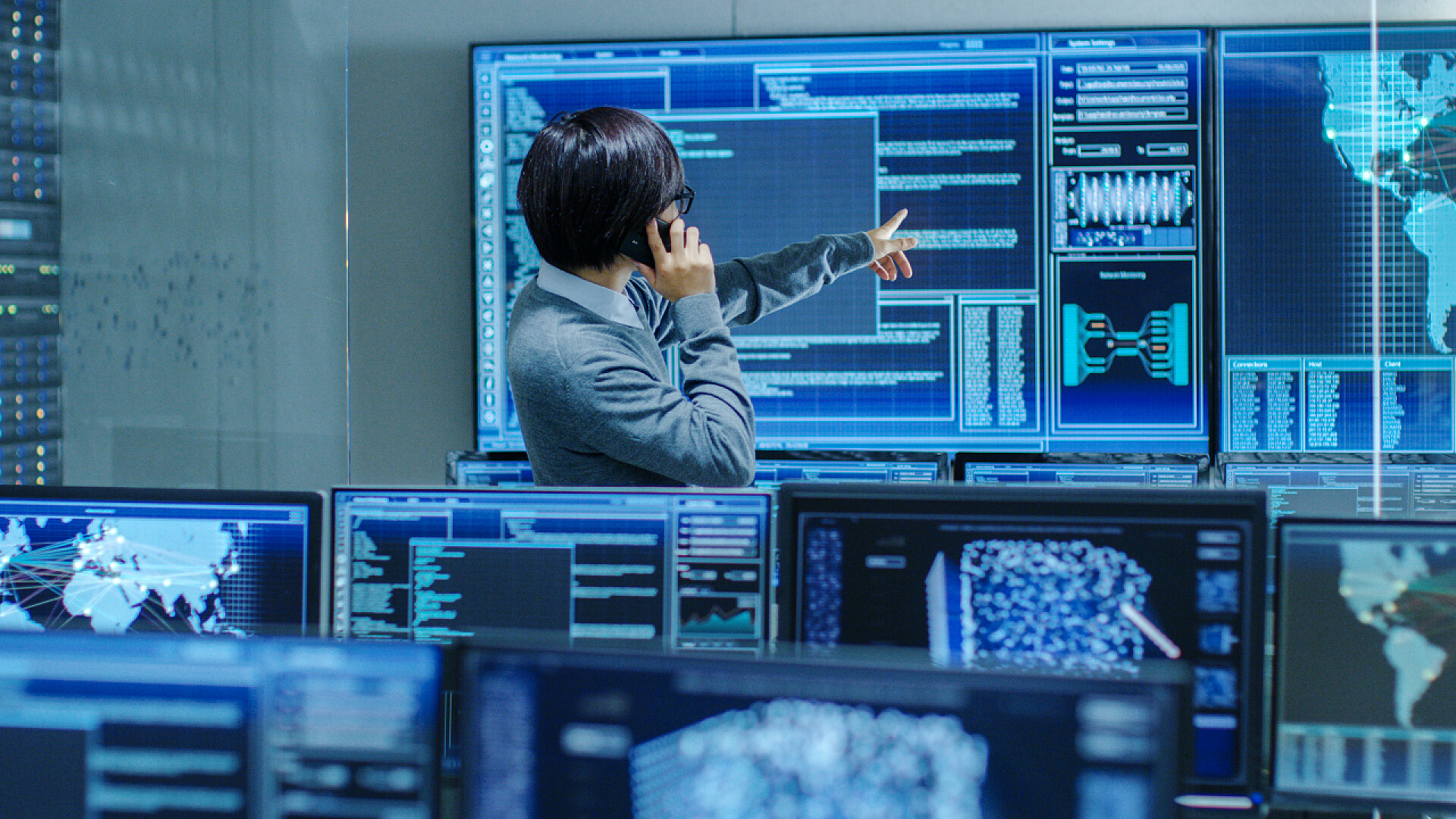 一个穿着西服的男人拿着手机在打电话在系统控制室 It 管理员在电话上交谈。他在一个高科技的设施, 工作在监控, 神经网络, 数据挖掘, 人工智能项目.