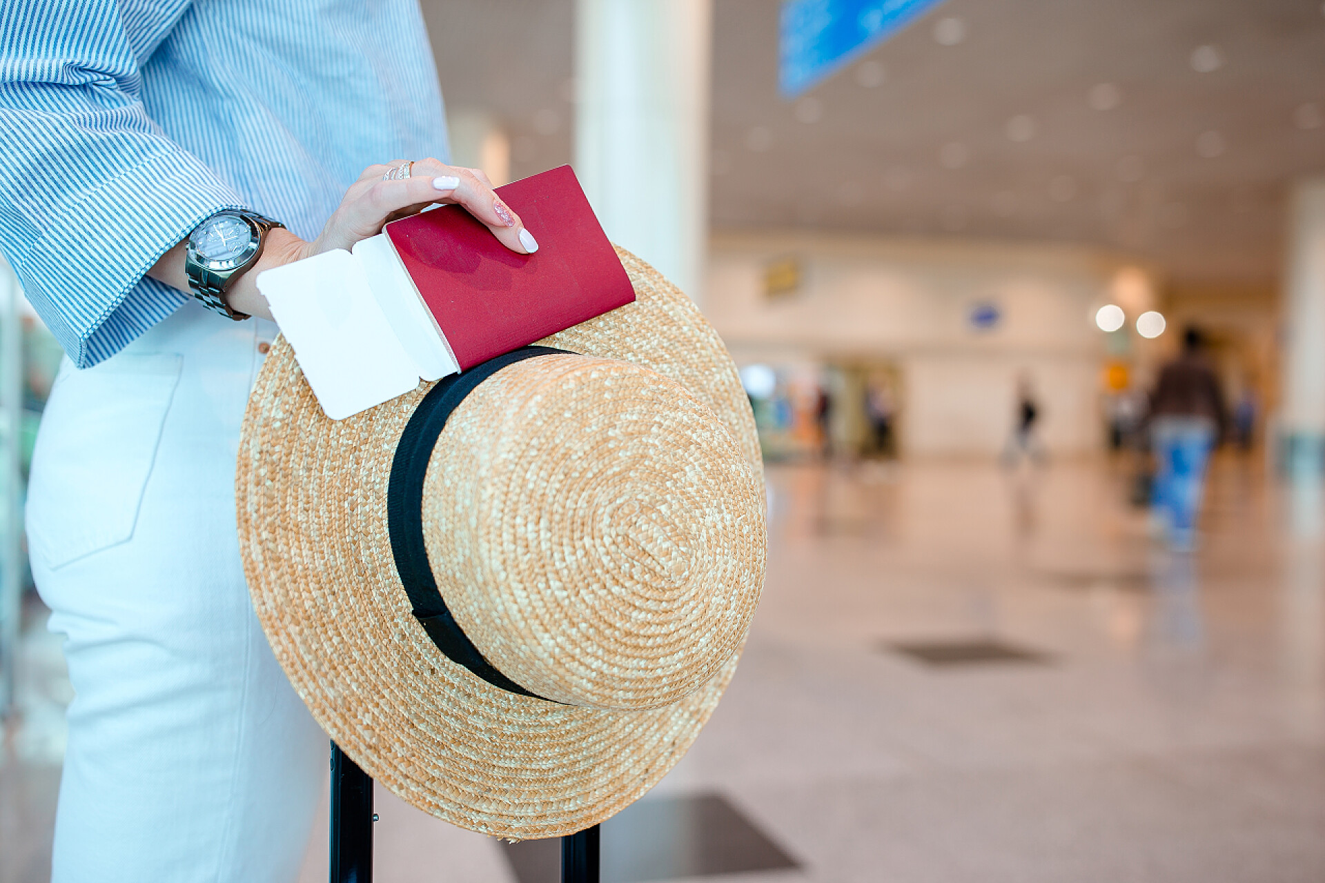 一个手里拿着护照和登机牌帽子和行李箱去旅游的女人在机场拦截持有护照和登机证的人