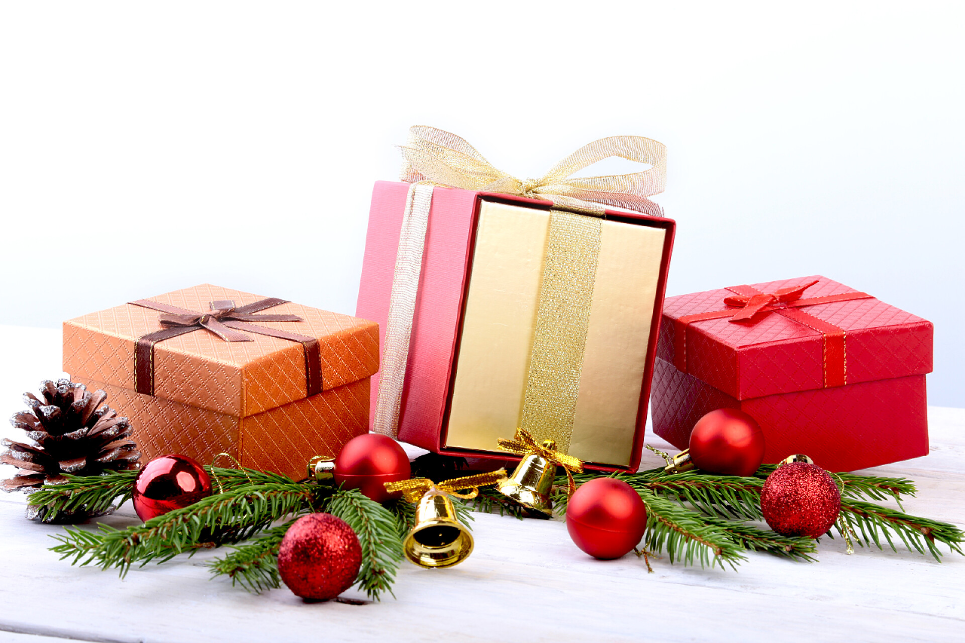 在白色的桌子上的三个小礼物盒子新年或圣诞节的装饰与礼品盒, 蜡烛和球。贺卡。选择性对焦, 复制空间.