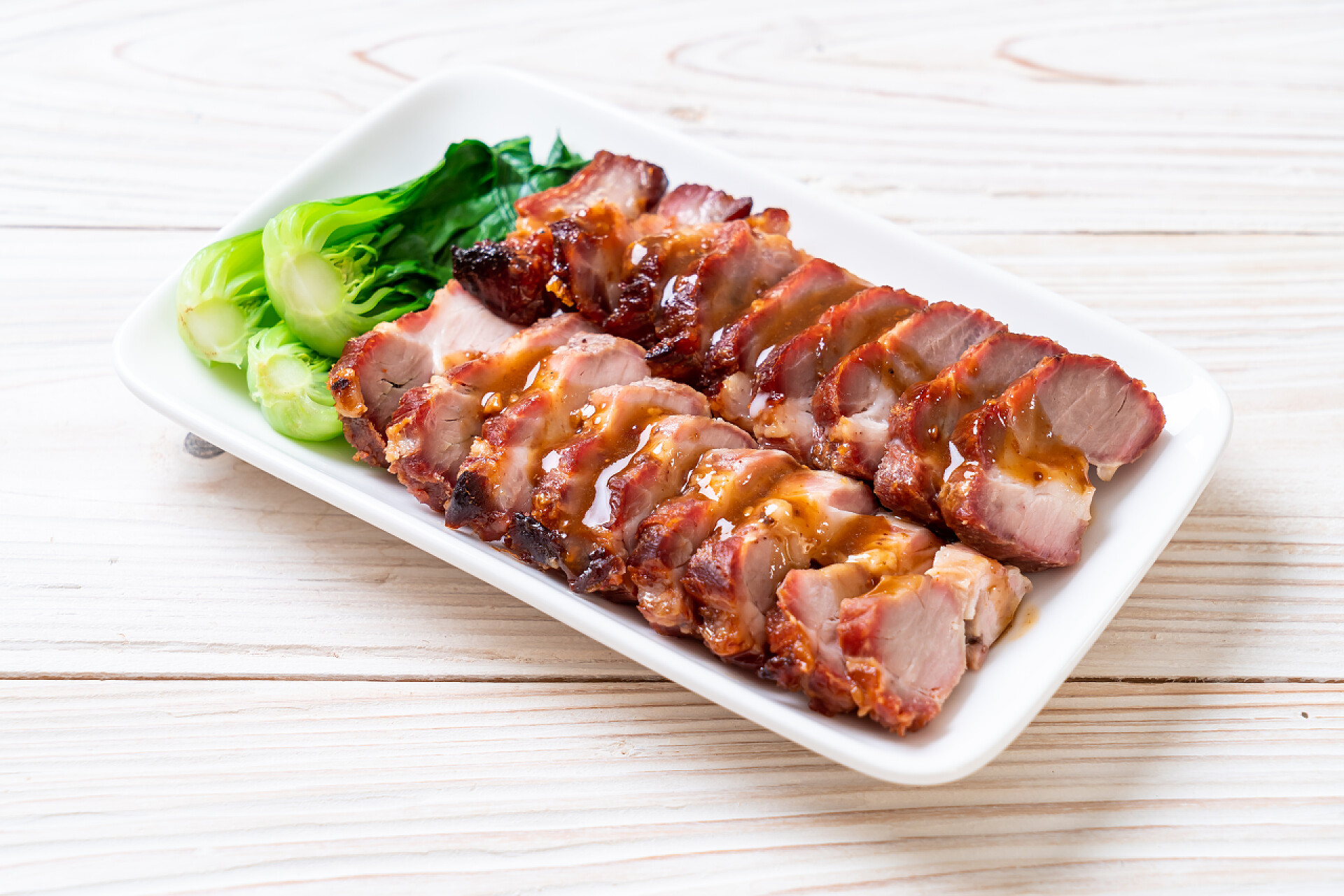 在浅色木质的桌子上有一盘白色的肉片烤烤肉红猪肉配酱