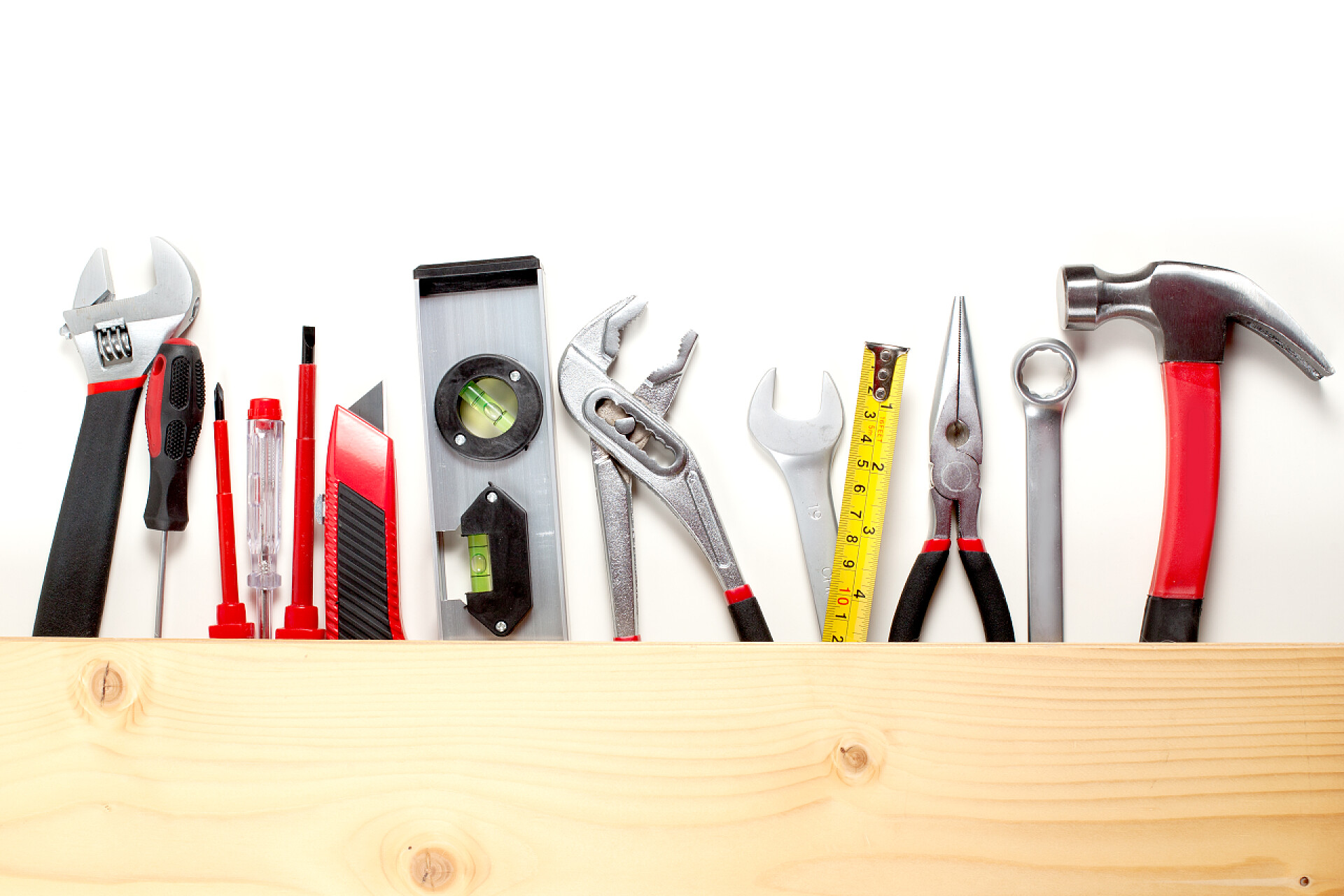 白色的背景墙前的木质桌子上有着各种各样的运用工具白色背景上各种施工工具的顶视图，维护理念