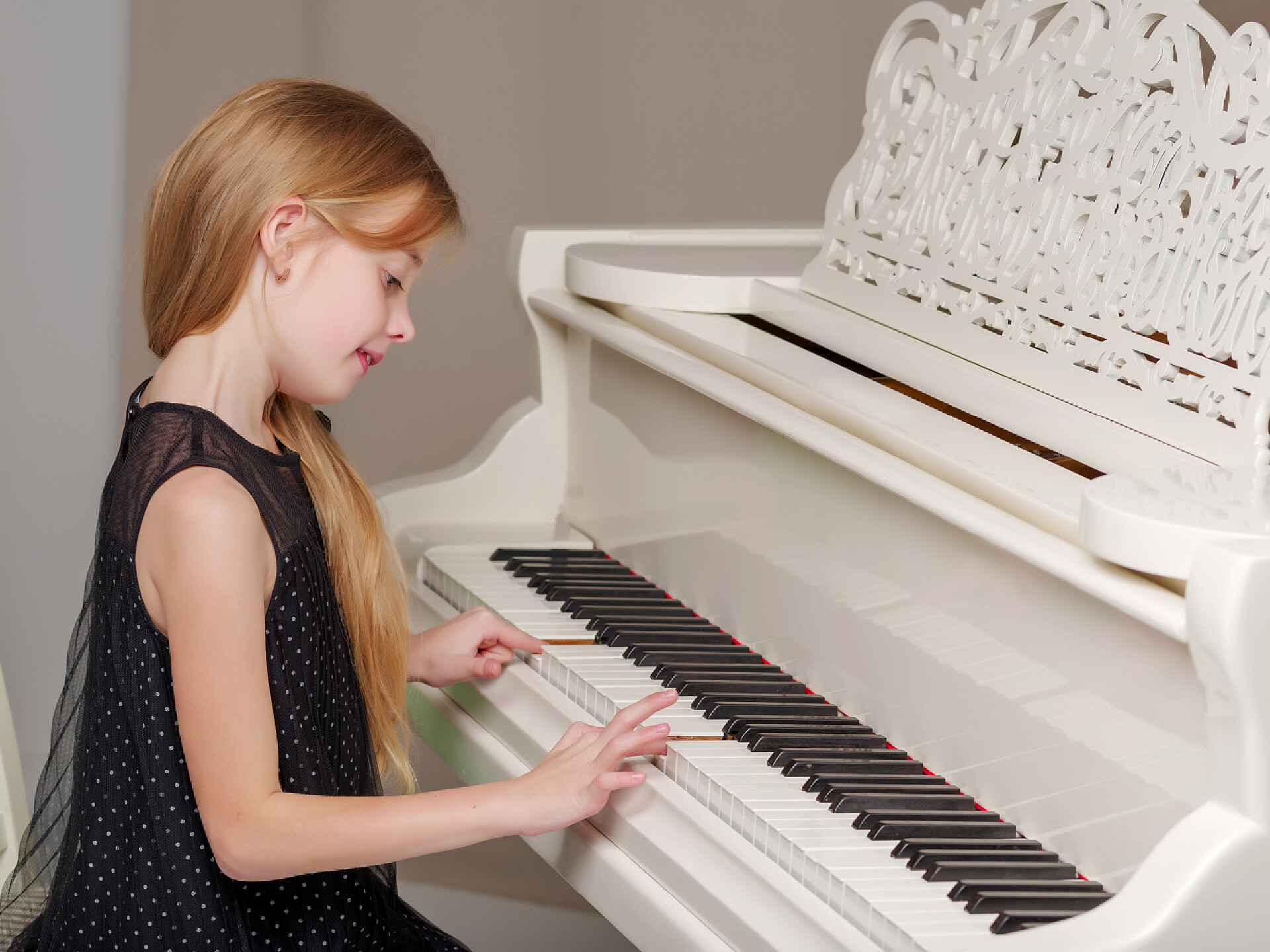 可爱的小女孩在弹钢琴漂亮的小女孩正在用一架白色的大钢琴弹奏.