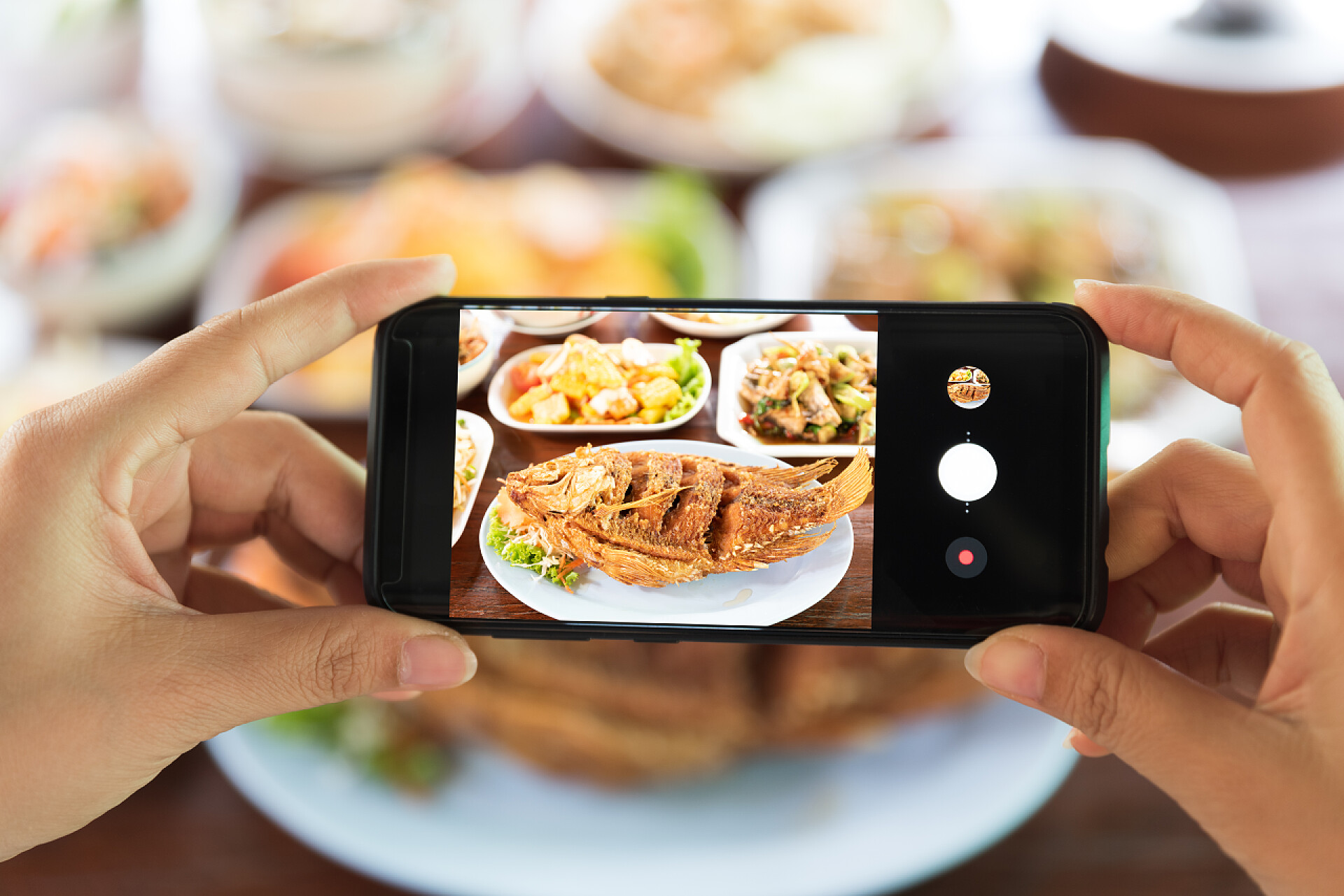 一双手拿着手机在拍照美食Woman taking a photo of food with smartphone in restaurant.