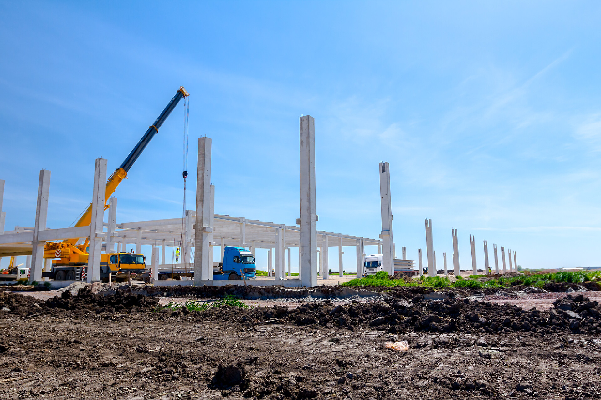 蓝天白云下施工队在工作移动起重机是工业建筑的大型混凝土骨架的总成。景观转化为城市地区与机械, 人们正在工作。查看施工现场.