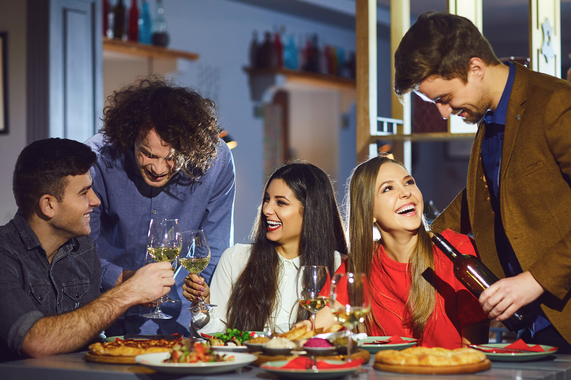 晚上五个好朋友在一起聚餐晚上快乐的朋友在餐馆里聊天. 