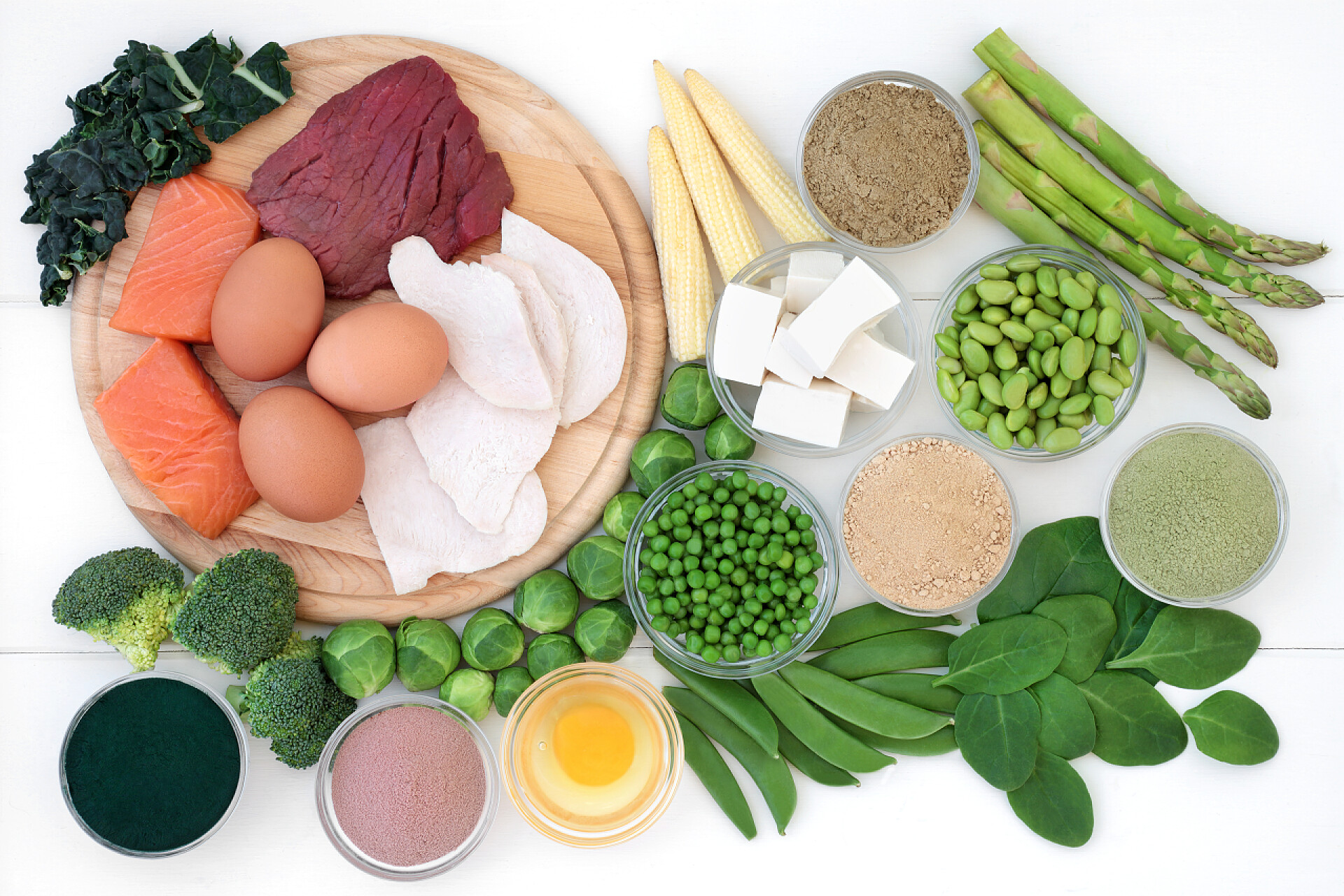 在白色桌子上展示的各种各样营养的蔬菜和肉类高蛋白食品, 包括肉类、鱼类、乳制品、豆类、补充粉末和大豆豆腐。在膳食纤维、抗氧化剂和维生素中工作。在乡村木背景的顶视图.