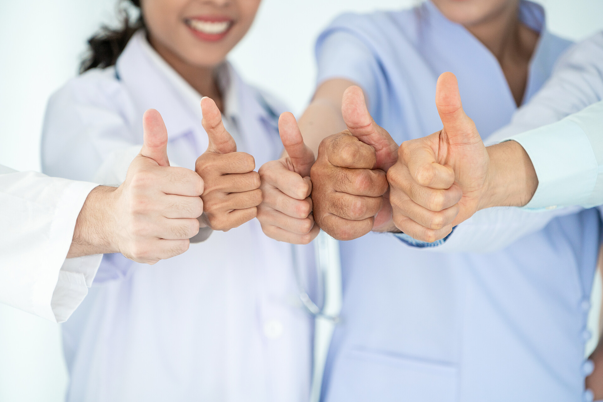 在白色的背景墙下五个医生的手伸出了大拇指医护人员组。与其他医生、护士和外科医生一起在医院办公室或诊所工作的专业医生。医疗技术研究院和医生员工服务理念.